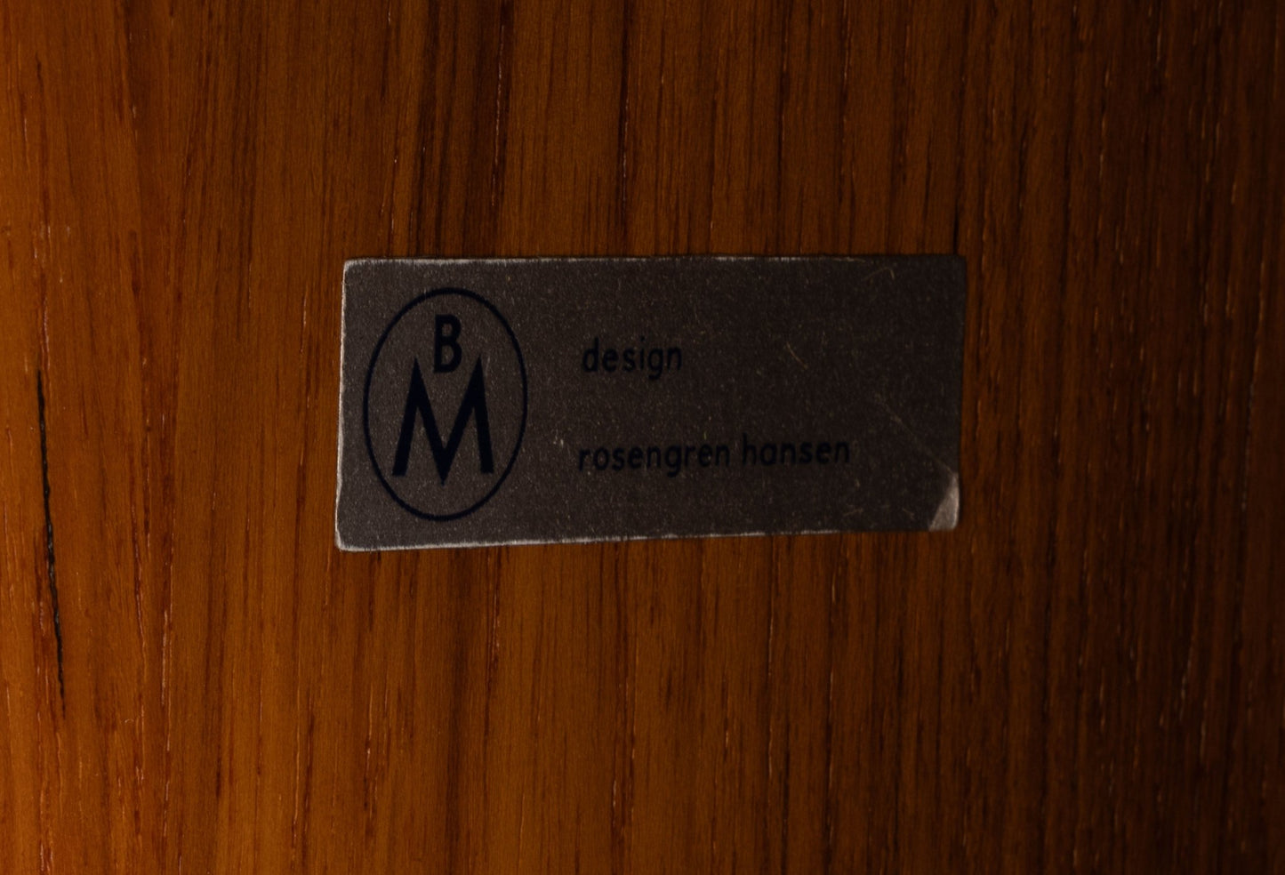 Close-up of vintage Brande Møbelindustri label on richly grained rosewood surface of mid-century modern furniture piece.