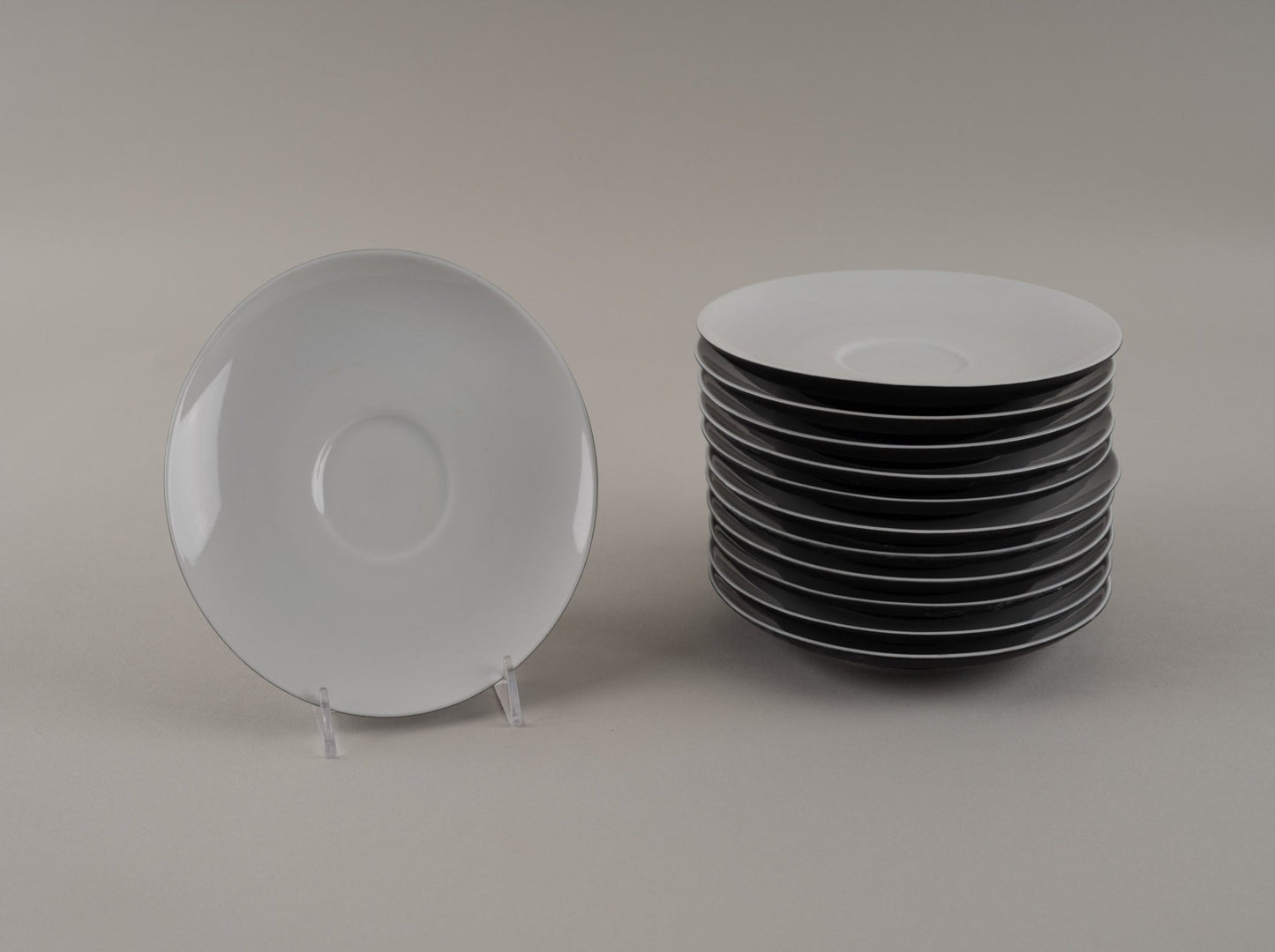 Stack of Rosenthal "Charcoal" eggshell black china plates with one plate displayed on a clear stand
