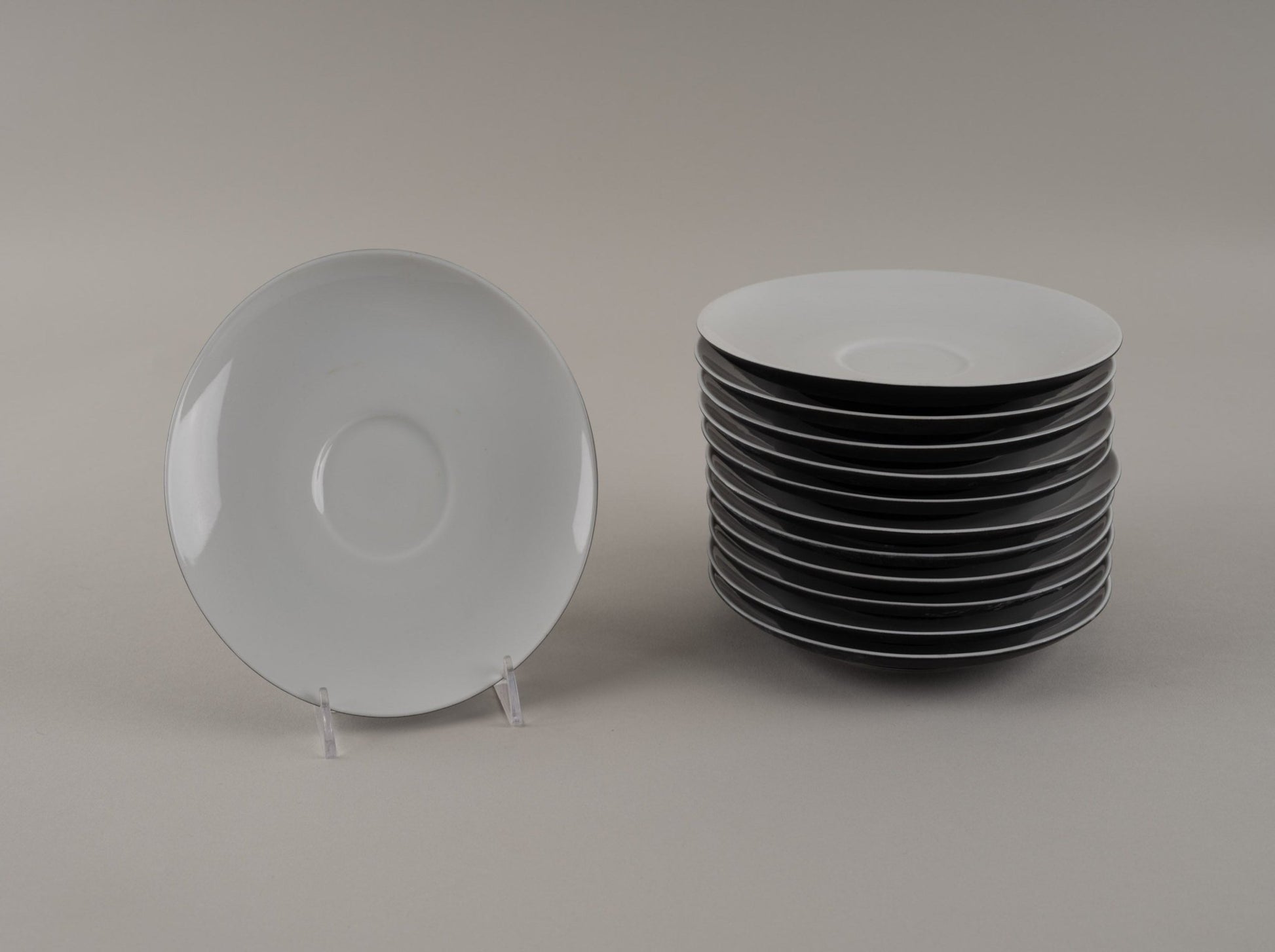 Stack of Rosenthal "Charcoal" eggshell black china plates with one plate displayed on a clear stand
