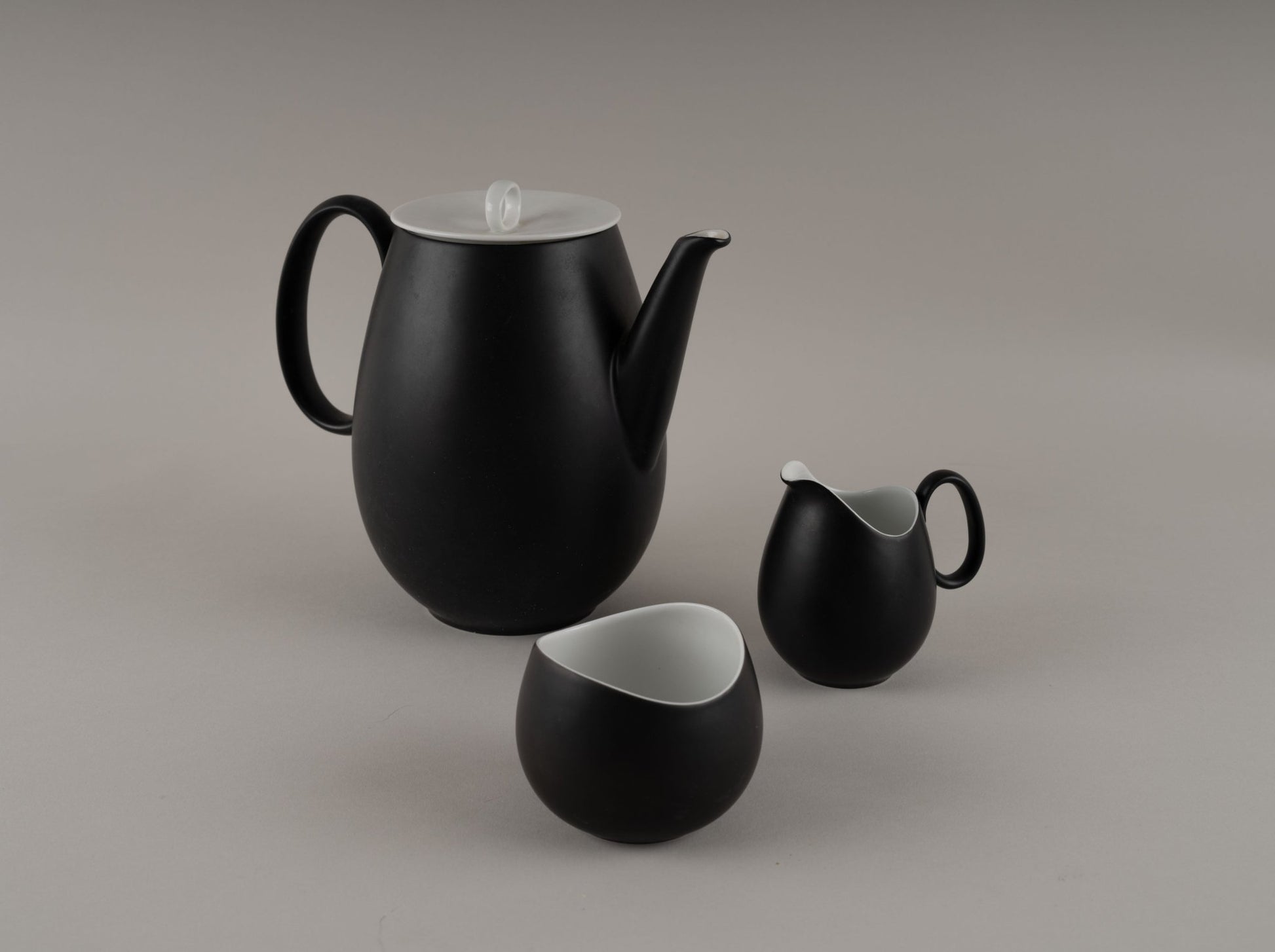 Three-piece Rosenthal “Charcoal” china set by Raymond Loewy, matte black exterior with glossy white interior, 1950s design.