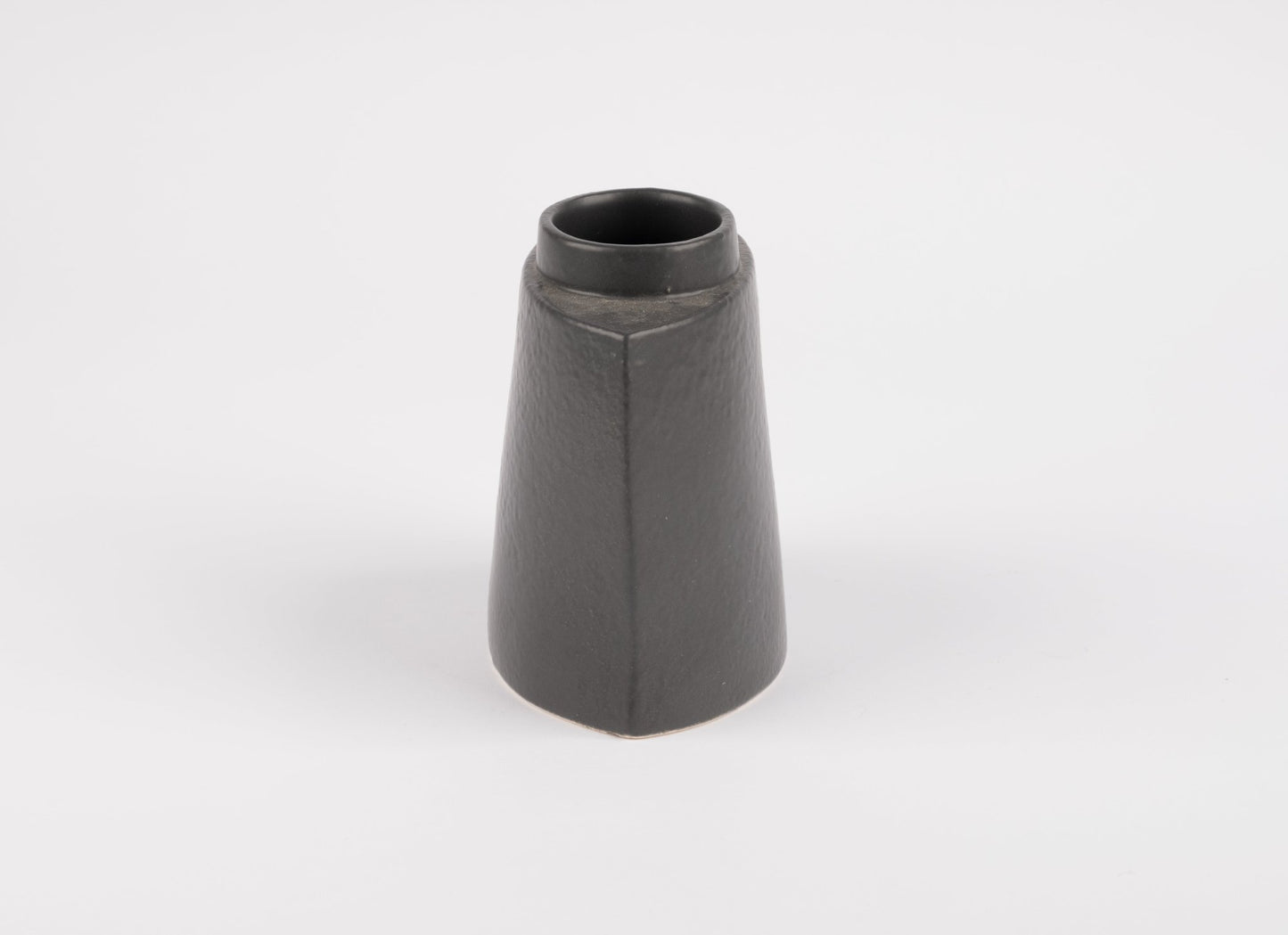 Handcrafted black stoneware vase with asymmetrical faceted silhouette and matte charcoal glaze on white background