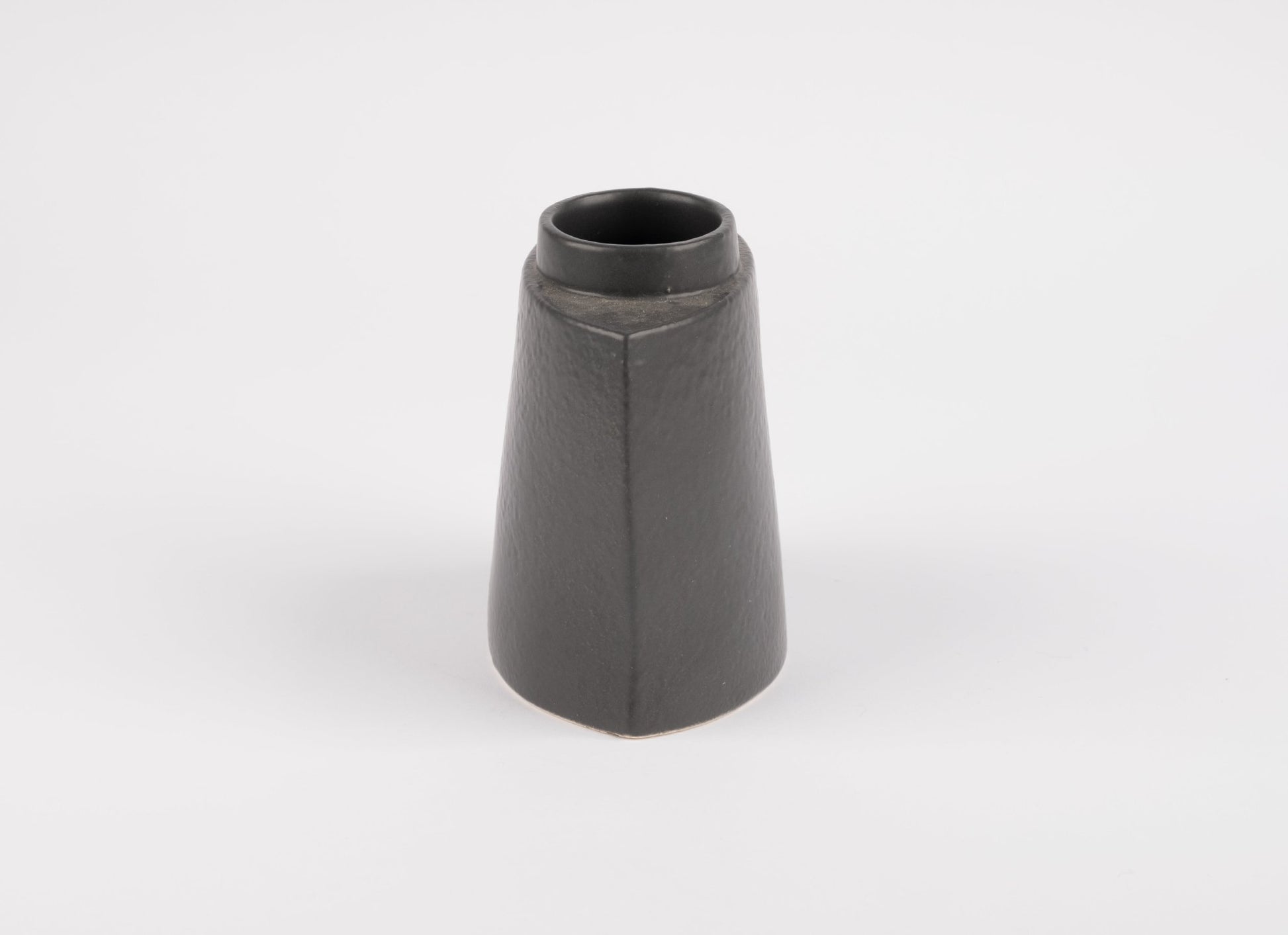 Handcrafted black stoneware vase with asymmetrical faceted silhouette and matte charcoal glaze on white background