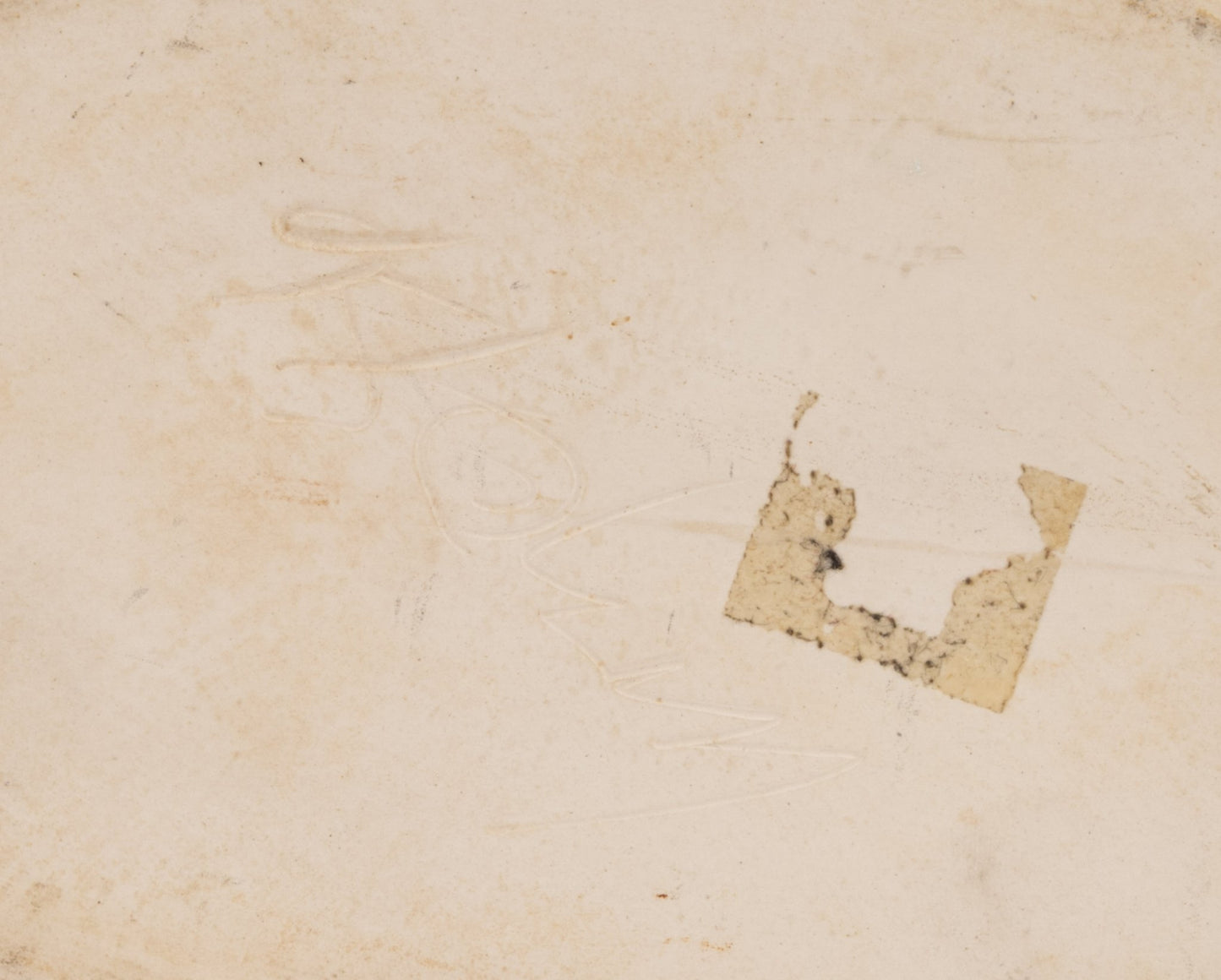 Close-up of the base of a dark stoneware vase showing handwritten marks and worn label residue on matte surface