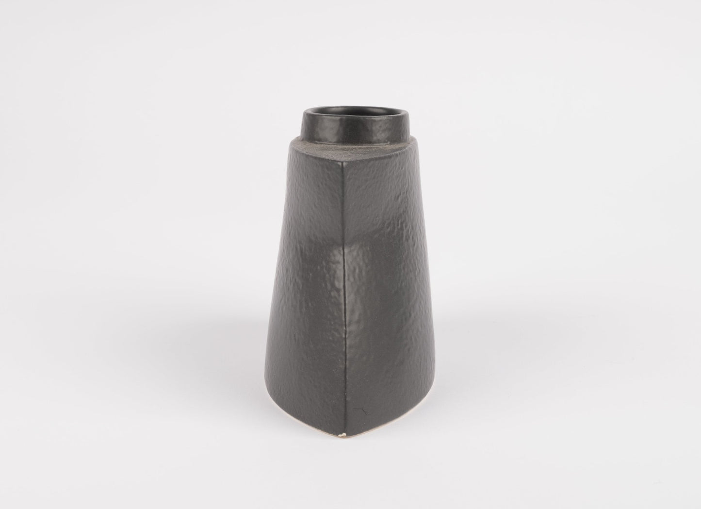 Handcrafted black stoneware vase with asymmetrical faceted silhouette and matte charcoal glaze on white background