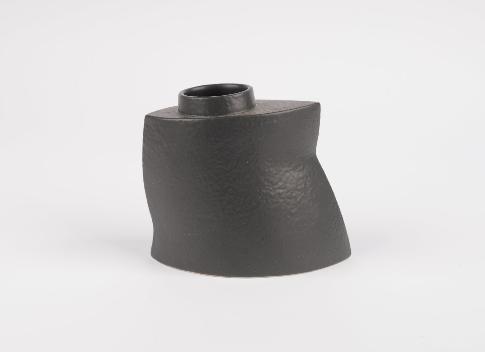 Sculptural black stoneware vase with asymmetrical faceted silhouette and matte charcoal finish on white background