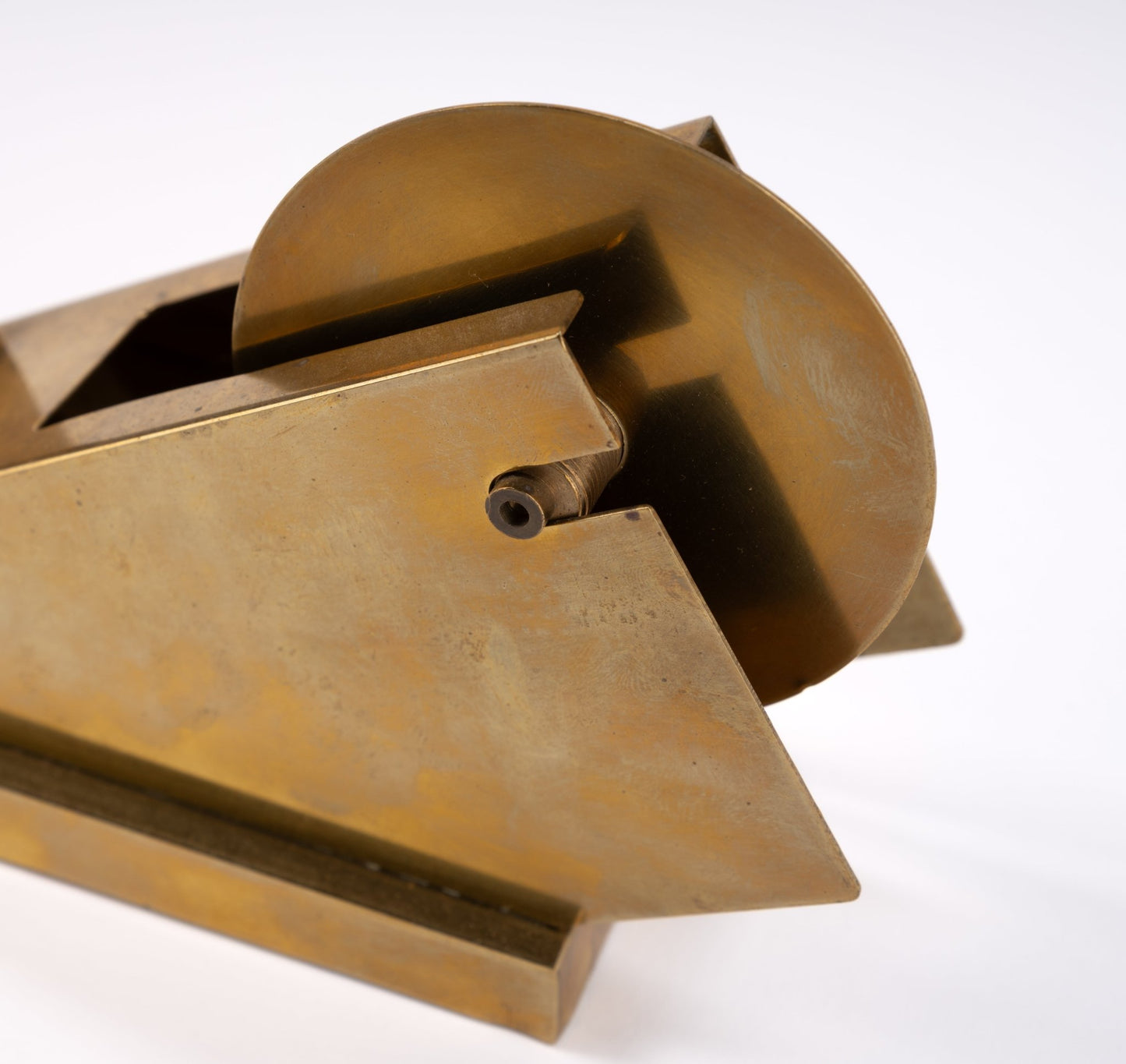 Vintage sculptural tape dispenser in solid brass with minimalist geometric form on white background