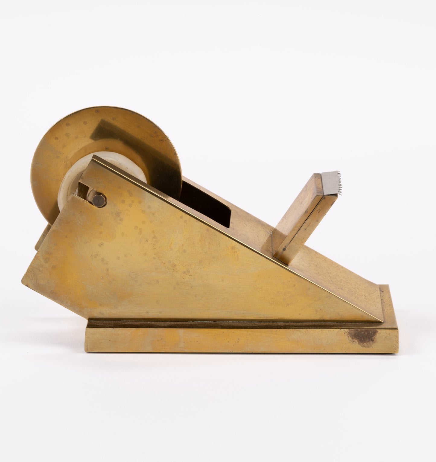 Vintage sculptural brass tape dispenser with minimalist angular form and solid metal build on white background