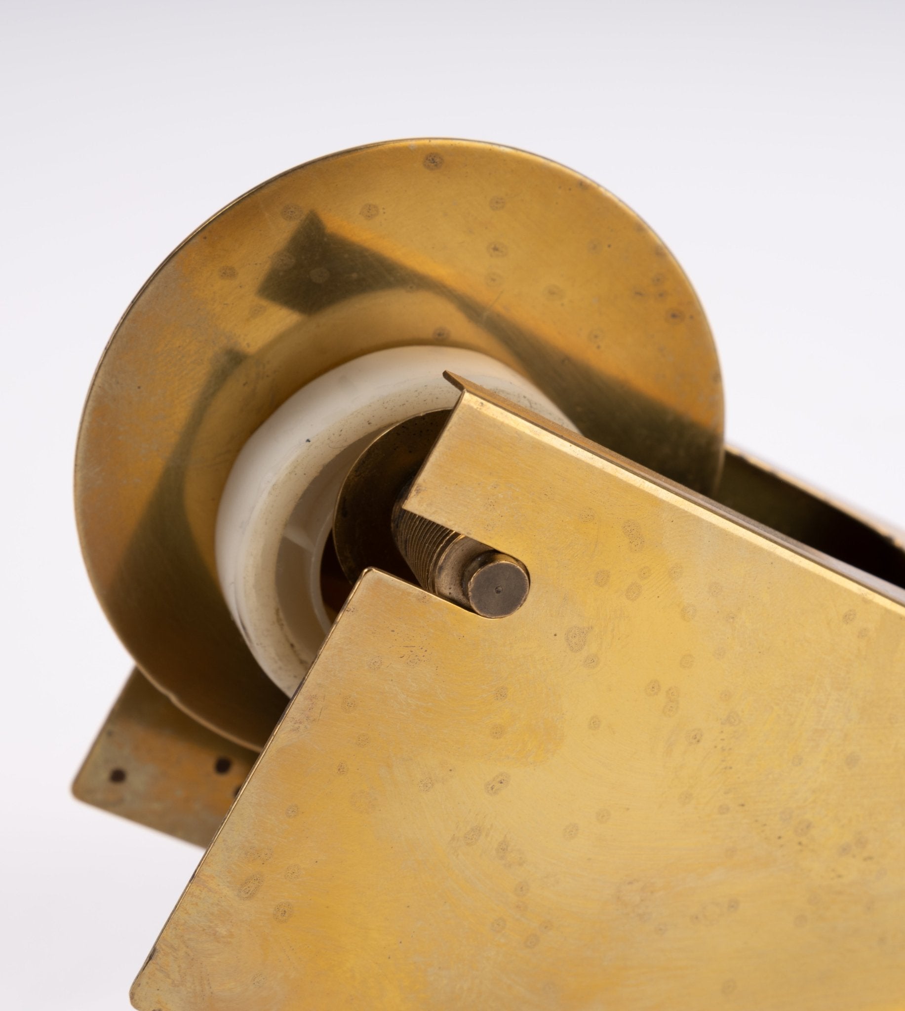 Close-up of vintage sculptural brass tape dispenser with minimalist angular design and solid brass construction