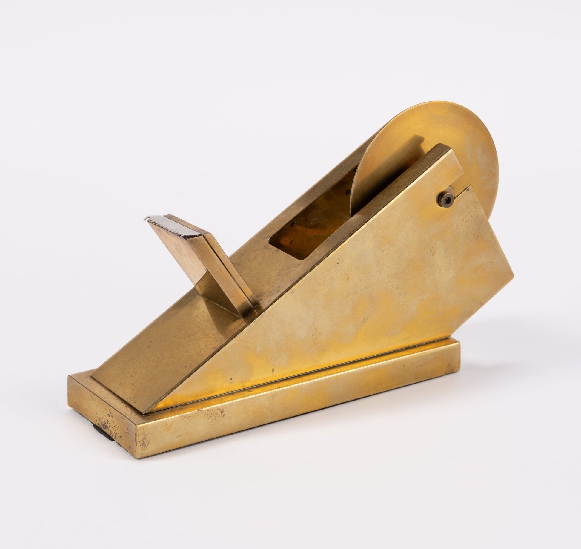 Vintage sculptural solid brass tape dispenser with minimalist geometric form and polished finish on white background