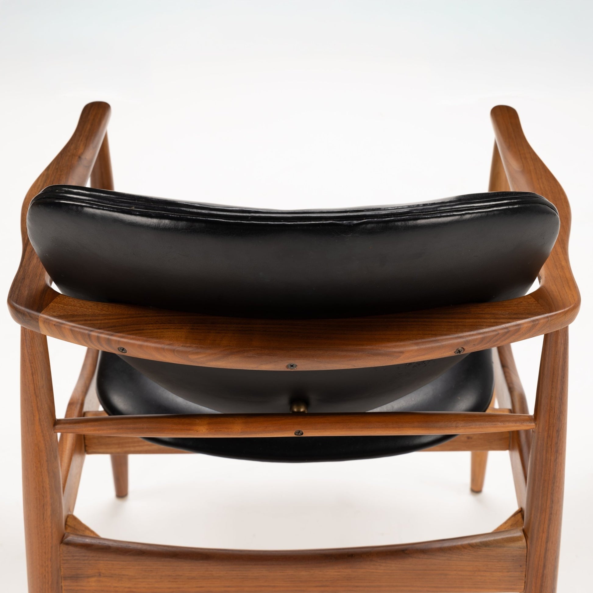 Set of 4 Walnut Dining Armchairs Attributed to Finn Juhl showing the gently curved walnut frame and smooth black leather backrest, embodying mid century modern seating style.