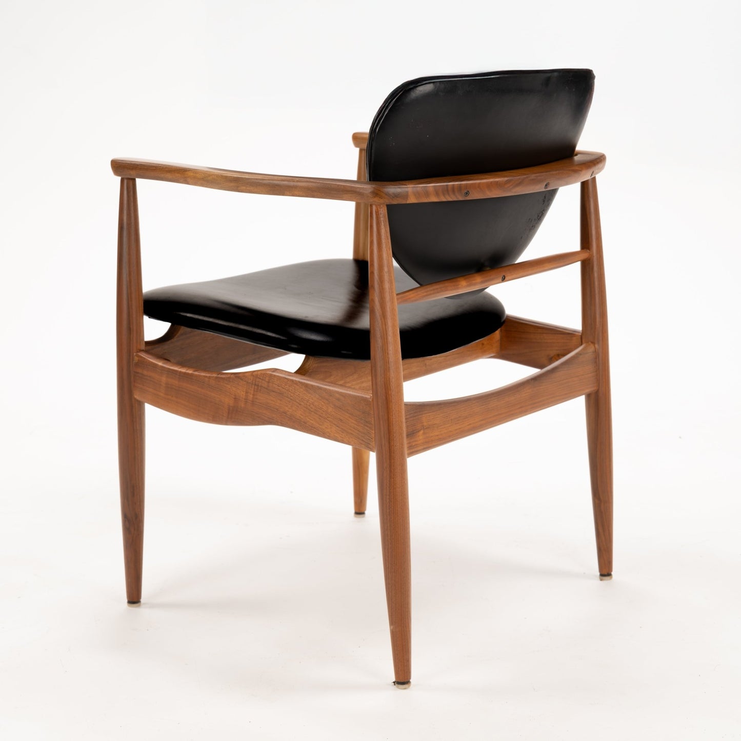 Set of 4 Walnut Dining Armchairs Attributed to Finn Juhl featuring smooth black leather cushions and sculpted walnut frames with tapered legs, embodying vintage Danish mid century modern seating design.