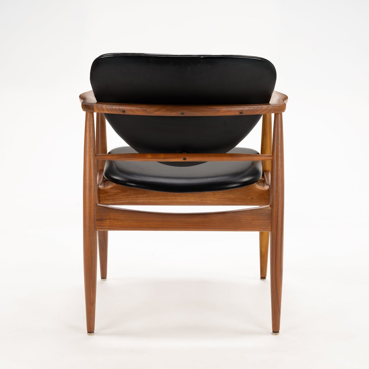 Rear view of the Set of 4 Walnut Dining Armchairs Attributed to Finn Juhl, showcasing the smooth curved walnut frame and black leather upholstered backrest and seat, highlighting mid century modern design.