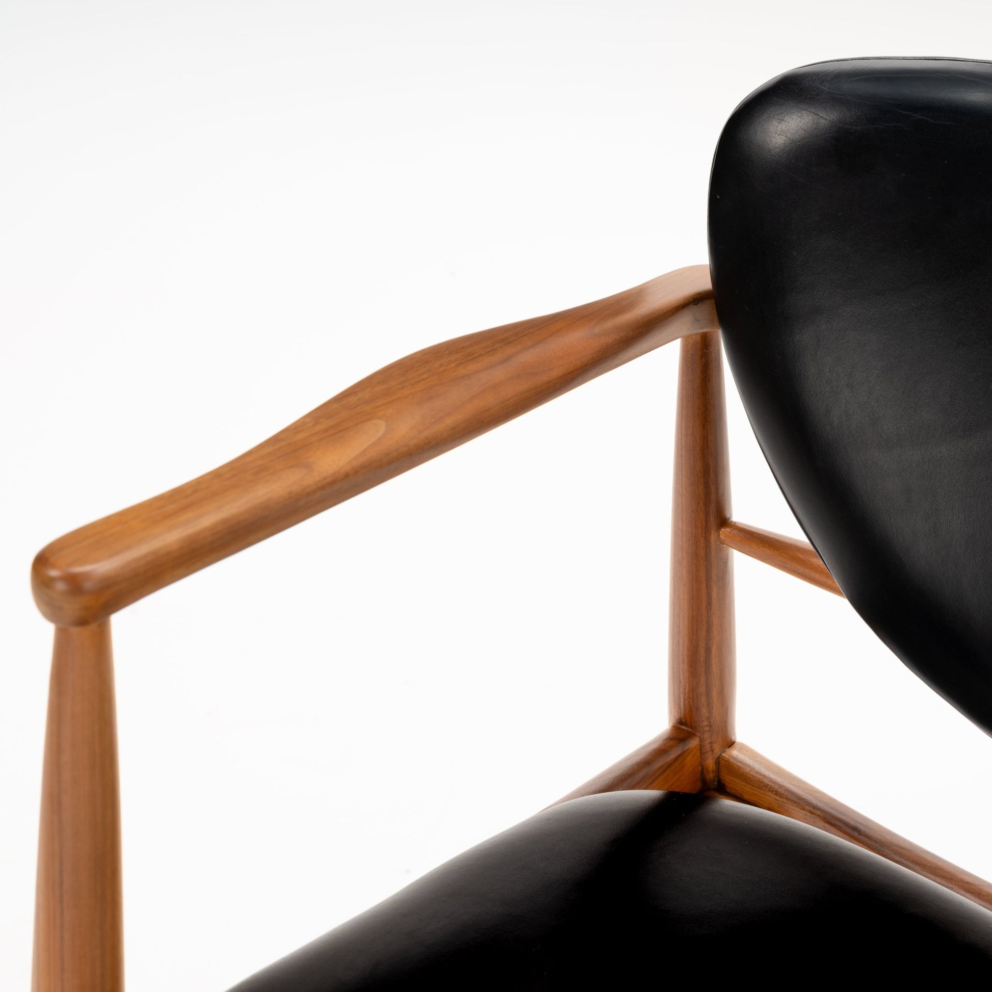 Set of 4 Walnut Dining Armchairs Attributed to Finn Juhl featuring sculpted walnut frames with elegantly curved armrests and smooth black leather upholstery, showcasing mid century modern seating craftsmanship.