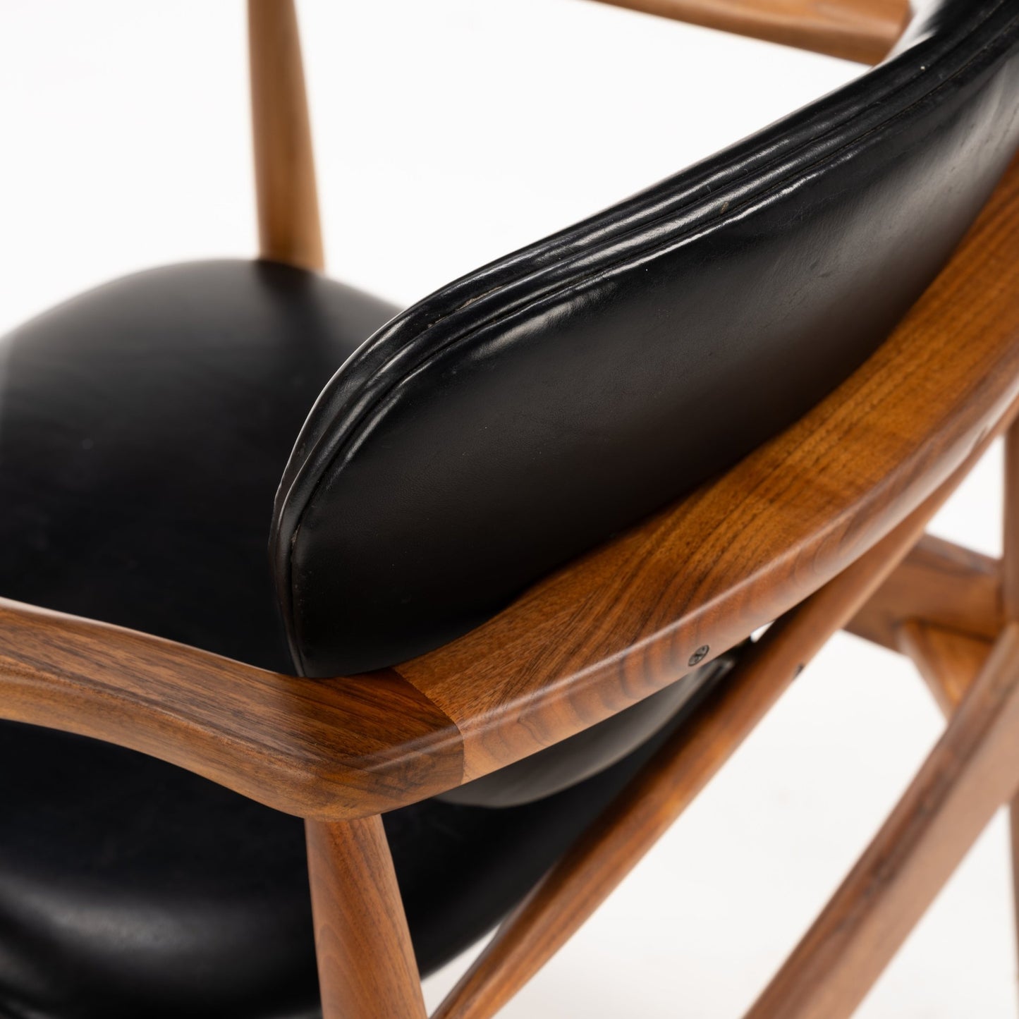 Close-up of the elegant curved walnut frame paired with smooth black leather upholstery on the backrest and seat of the Set of 4 Walnut Dining Armchairs Attributed to Finn Juhl, showcasing mid century modern seating design.
