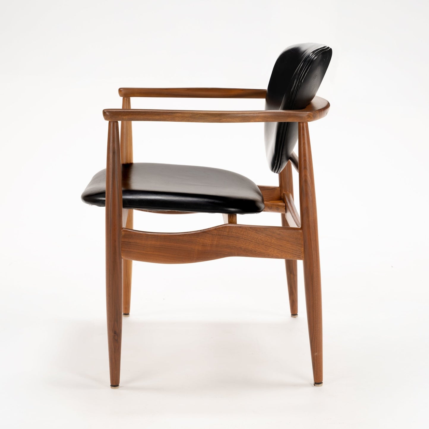 Set of 4 Walnut Dining Armchairs Attributed to Finn Juhl featuring sculpted walnut frames with gently curved armrests and black leather upholstery, showcasing vintage Danish mid century modern seating design.