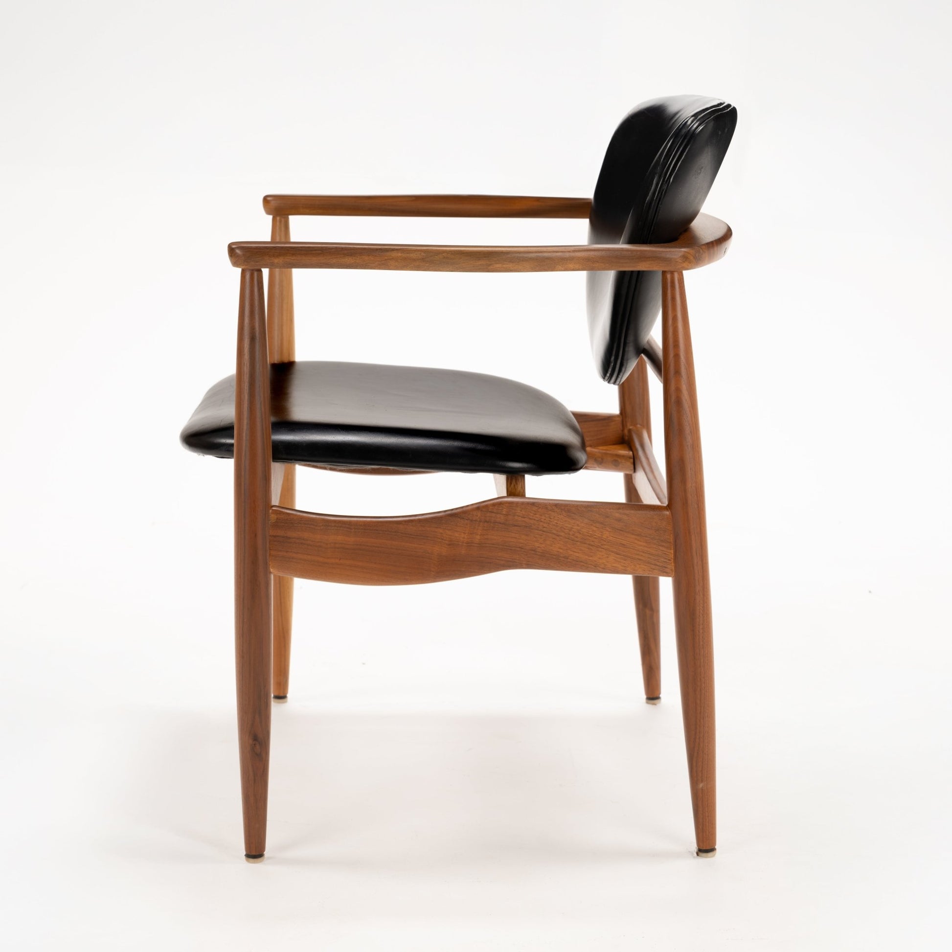 Set of 4 Walnut Dining Armchairs Attributed to Finn Juhl featuring sculpted walnut frames with gently curved armrests and black leather upholstery, showcasing vintage Danish mid century modern seating design.