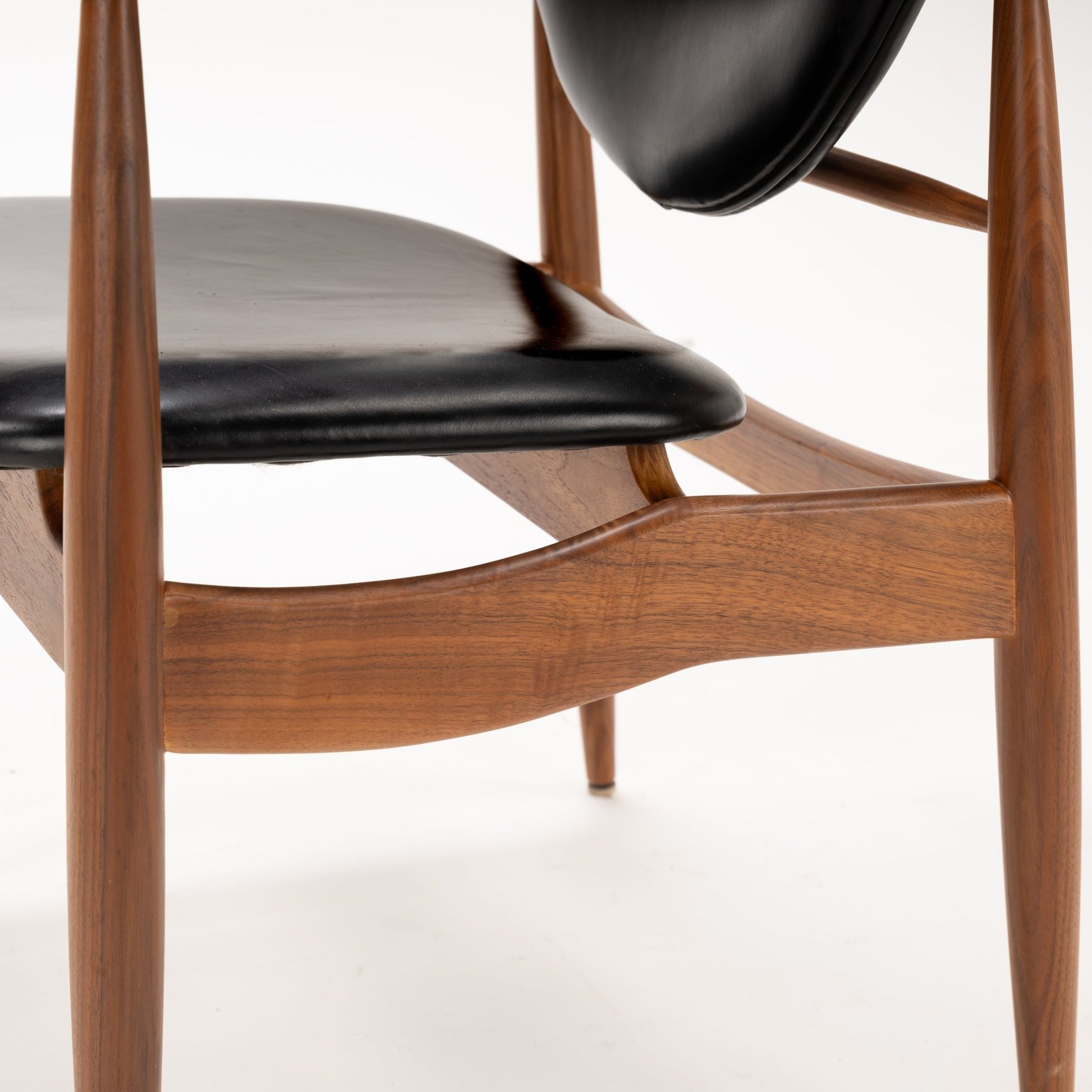 Close-up of black leather seat and sculpted walnut wood frame highlighting smooth curves and fine craftsmanship of the Set of 4 Walnut Dining Armchairs Attributed to Finn Juhl, mid century modern seating design.