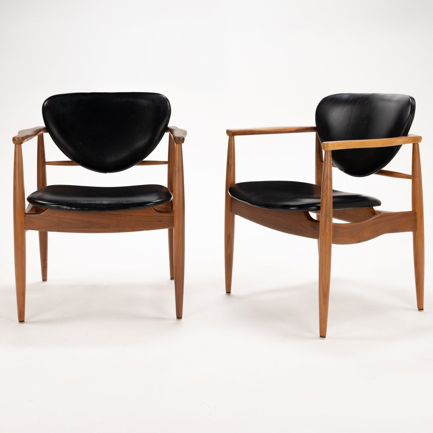 Set of 4 Walnut Dining Armchairs Attributed to Finn Juhl featuring sculpted walnut frames with gently curved arms and black leather upholstered seats and backrests, highlighting vintage Danish mid century modern seating design.