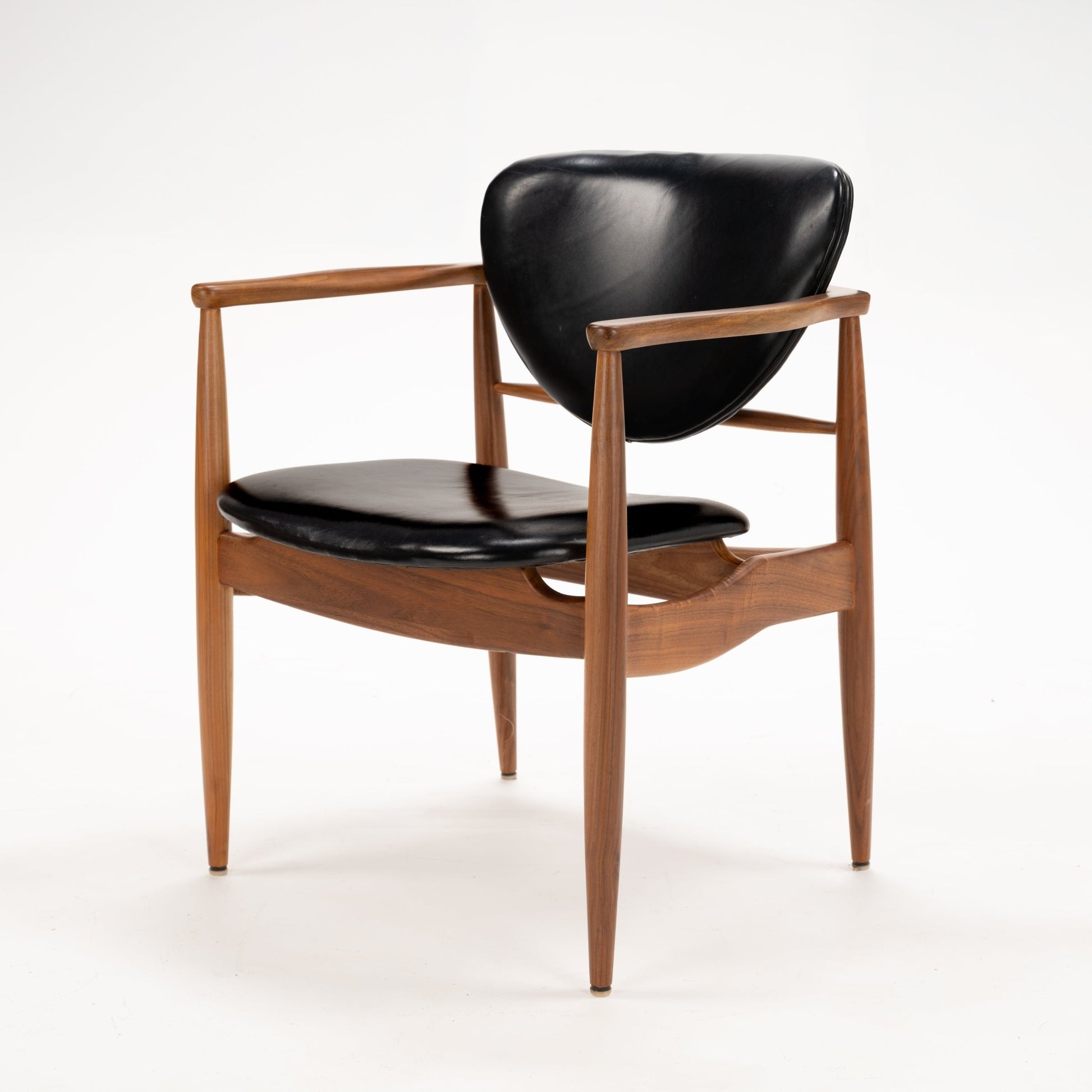 Set of 4 Walnut Dining Armchairs Attributed to Finn Juhl featuring sculpted walnut frames with sleek black leather cushions and gently tapered legs, exemplifying vintage Danish mid century modern seating design.