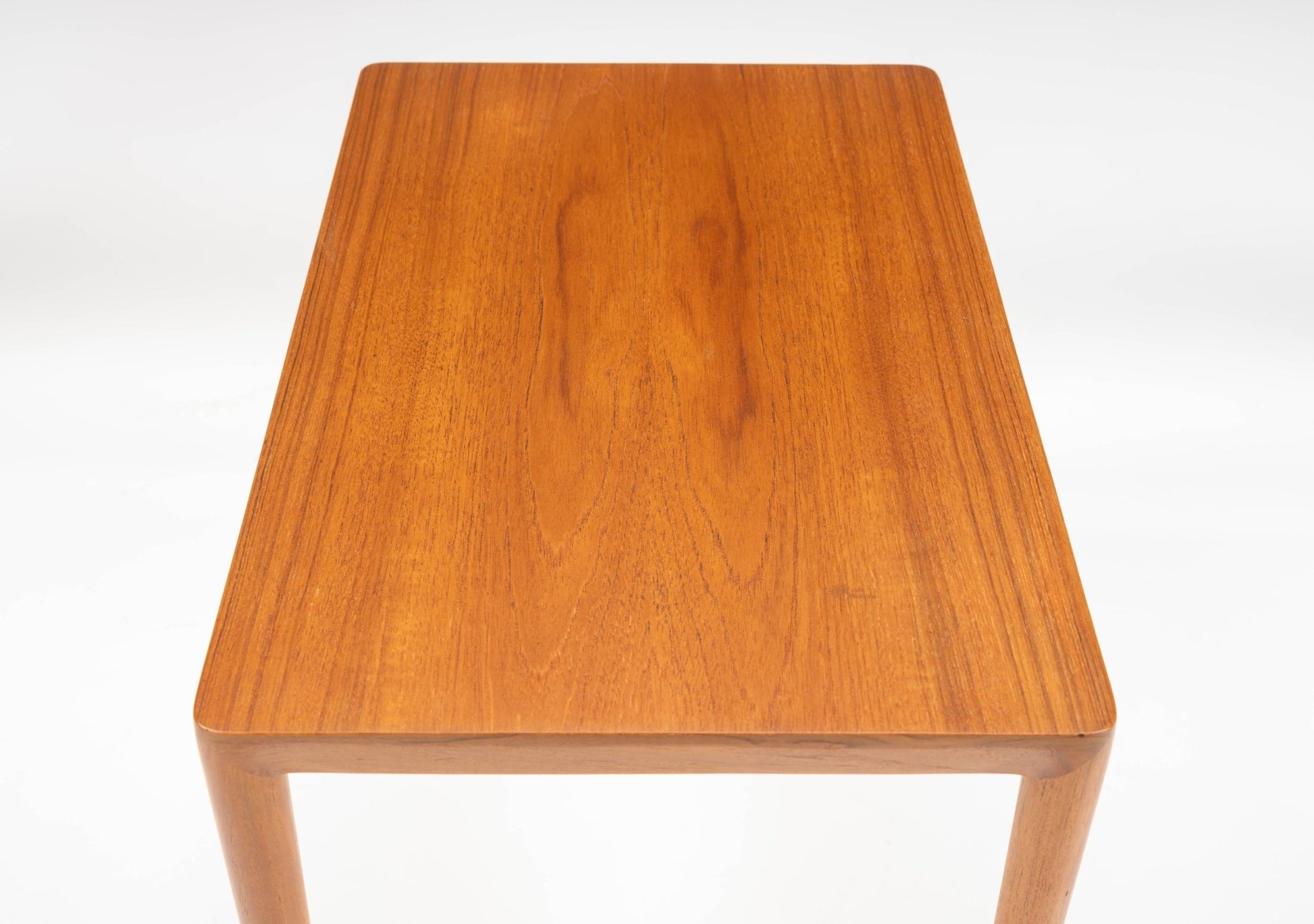 Rectangular mid-century modern teak side table with beveled edges and round tapered legs in Danish style.