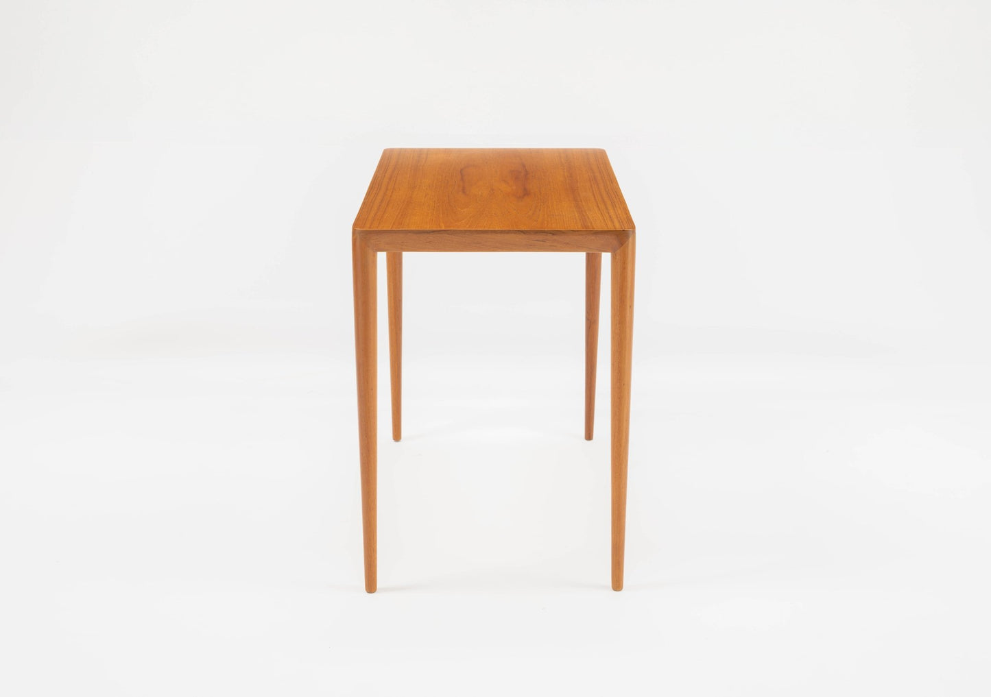 Mid-century modern teak side table in the manner of Severin Hansen with tapered legs and beveled edges on white background