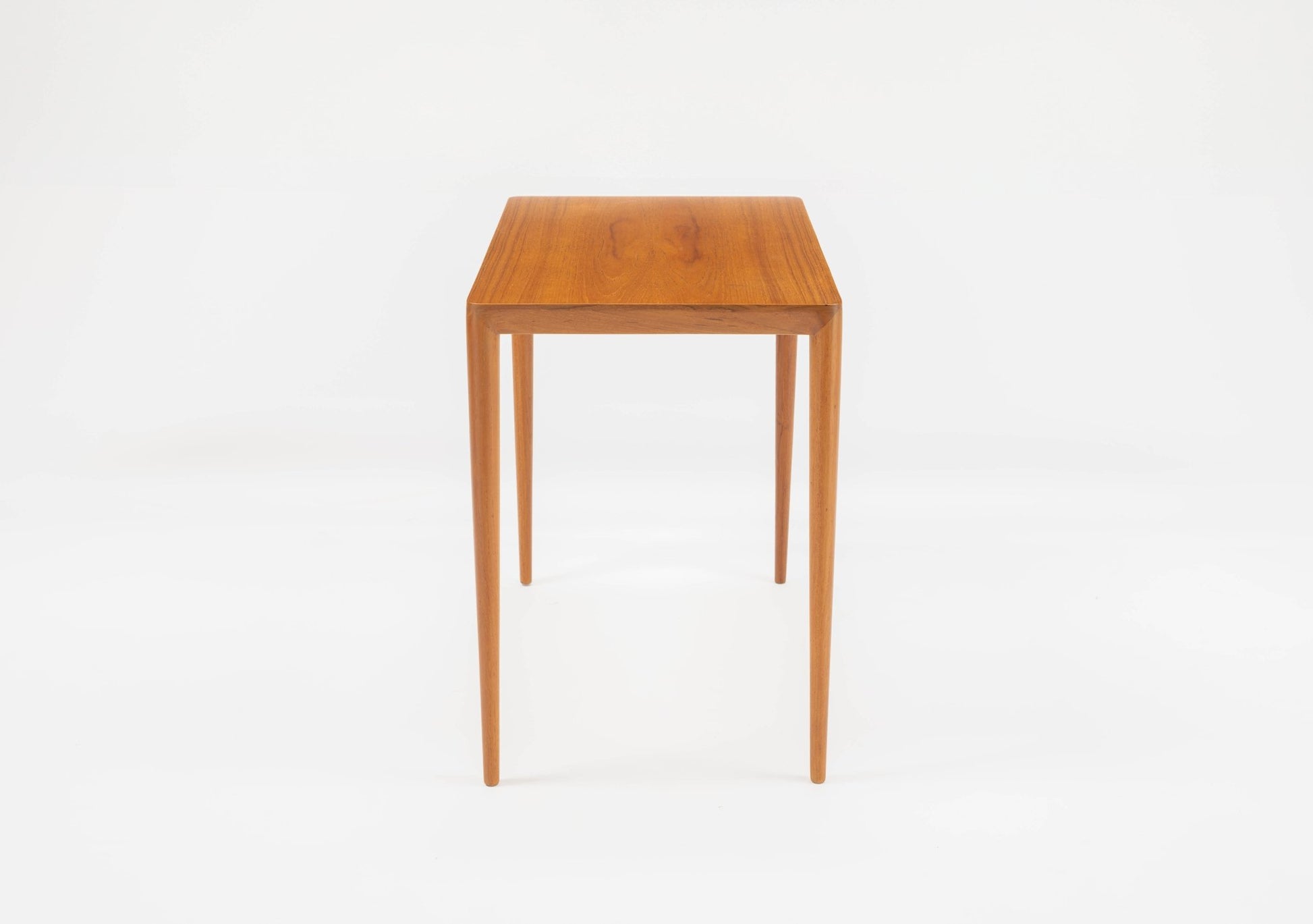 Mid-century modern teak side table in the manner of Severin Hansen with tapered legs and beveled edges on white background