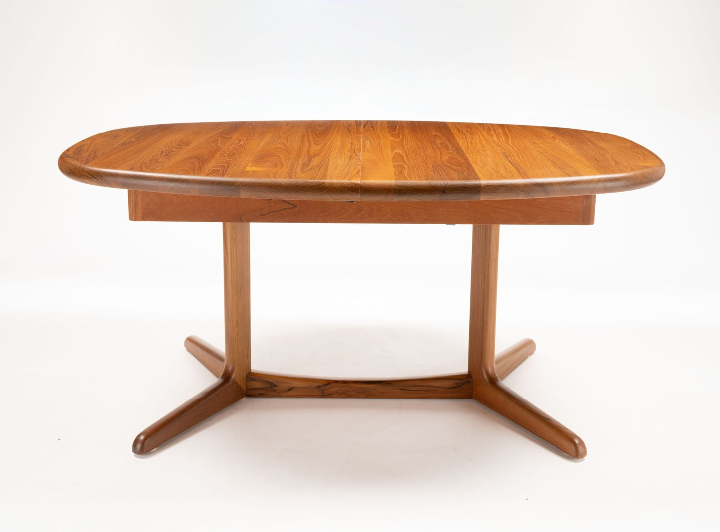 Mid-century modern teak racetrack dining table with curved edges and sturdy pedestal base on white background.