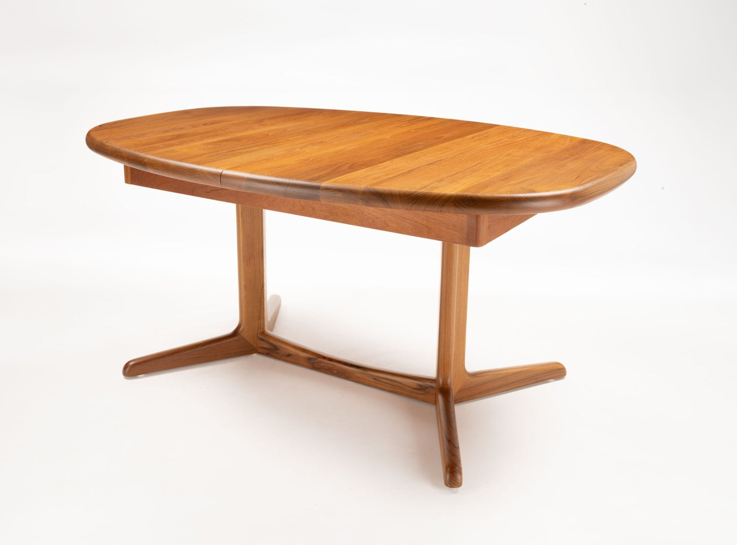 Mid-century modern teak racetrack dining table with rounded edges and sculptural wooden pedestal base on white background