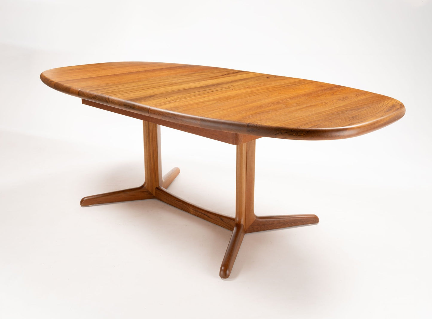 Mid-century modern Skovby teak racetrack dining table with smooth rounded edges and tapered legs on white background.