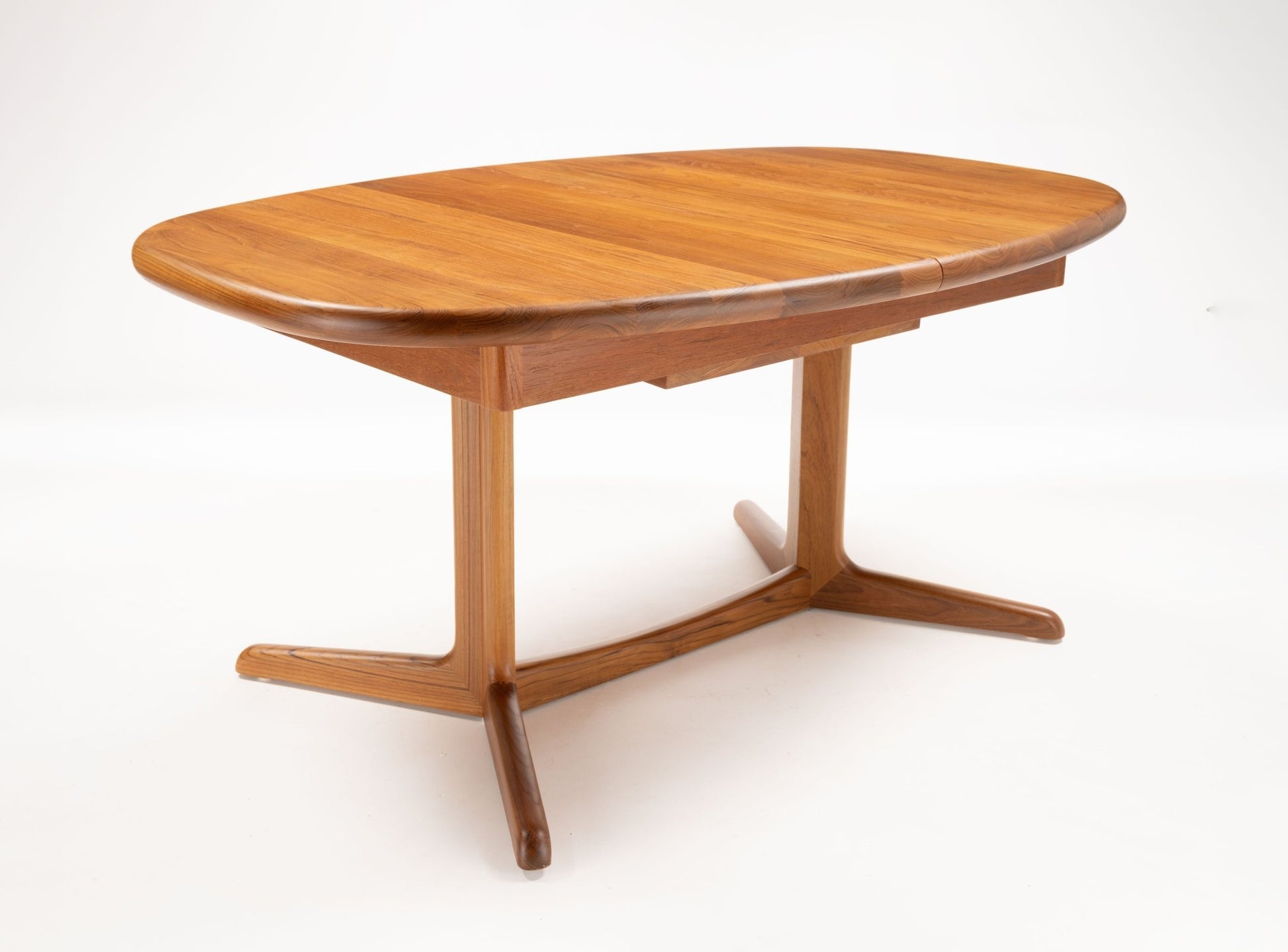 Mid-century modern teak racetrack dining table with rounded edges and T-shaped pedestal base in warm wood finish