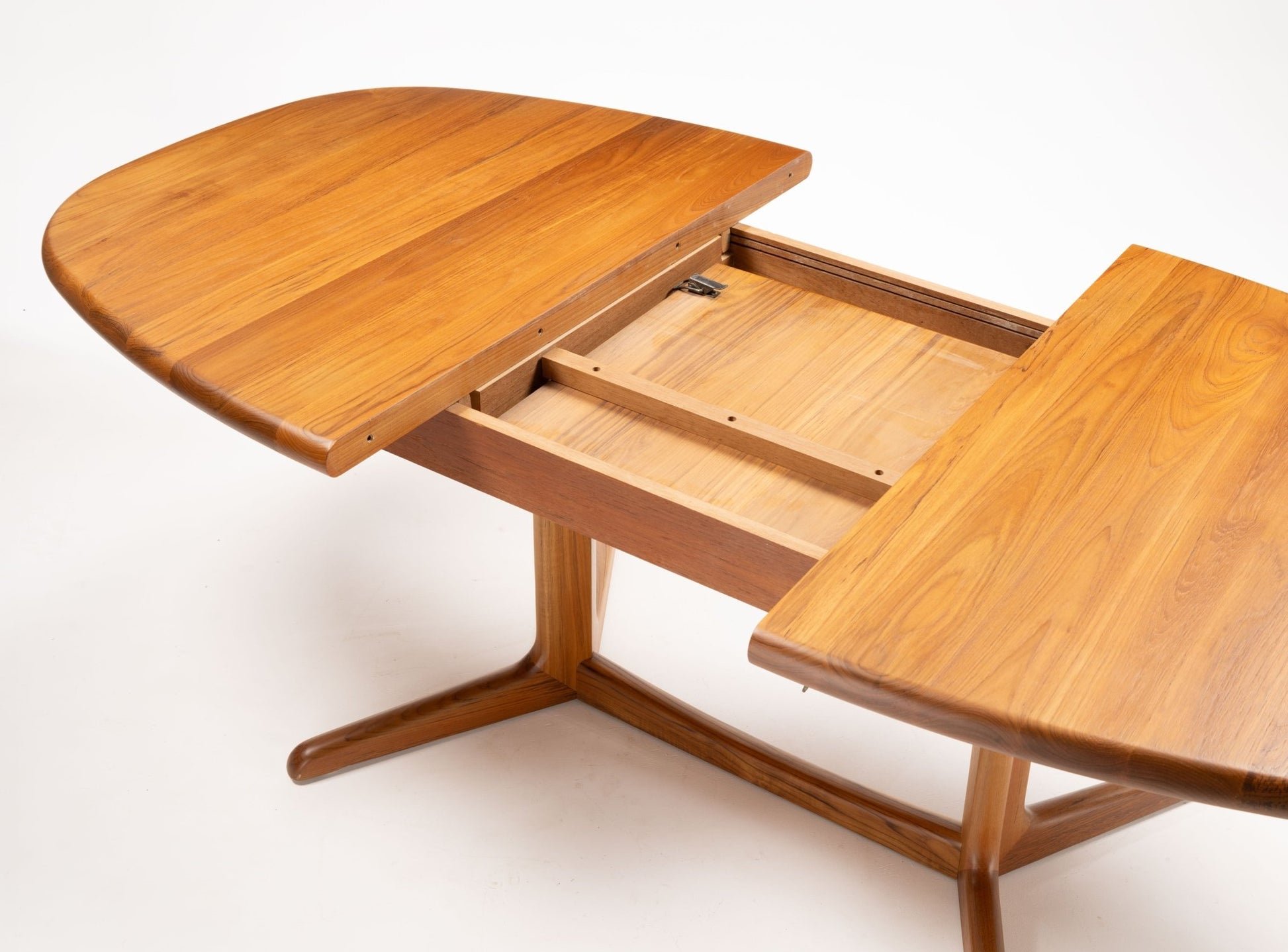 Mid-century modern teak racetrack dining table with curved ends and rectangular center, showcasing extension mechanism.