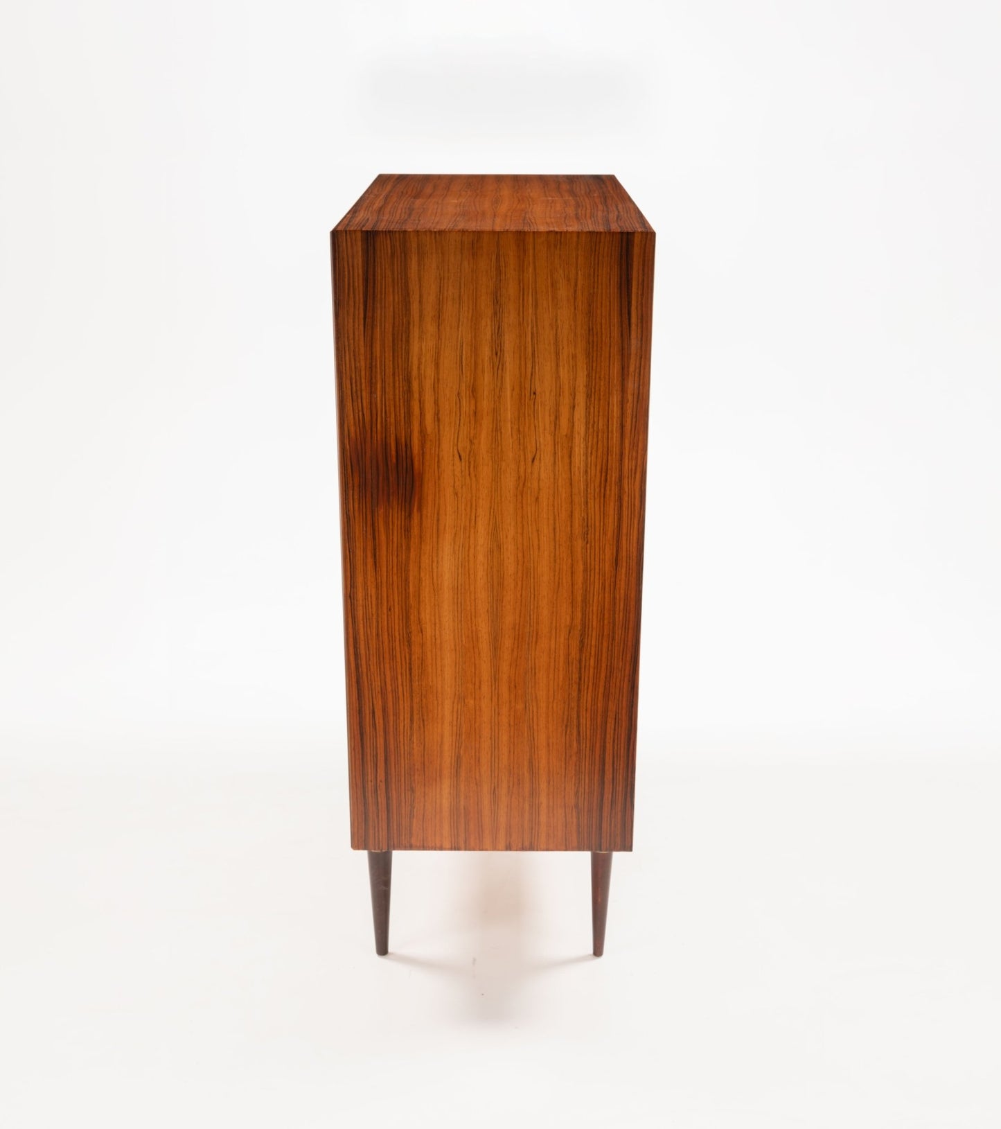 Side view of mid-century modern Svante Skogh rosewood dresser with slender tapered legs and bookmatched wood grain.