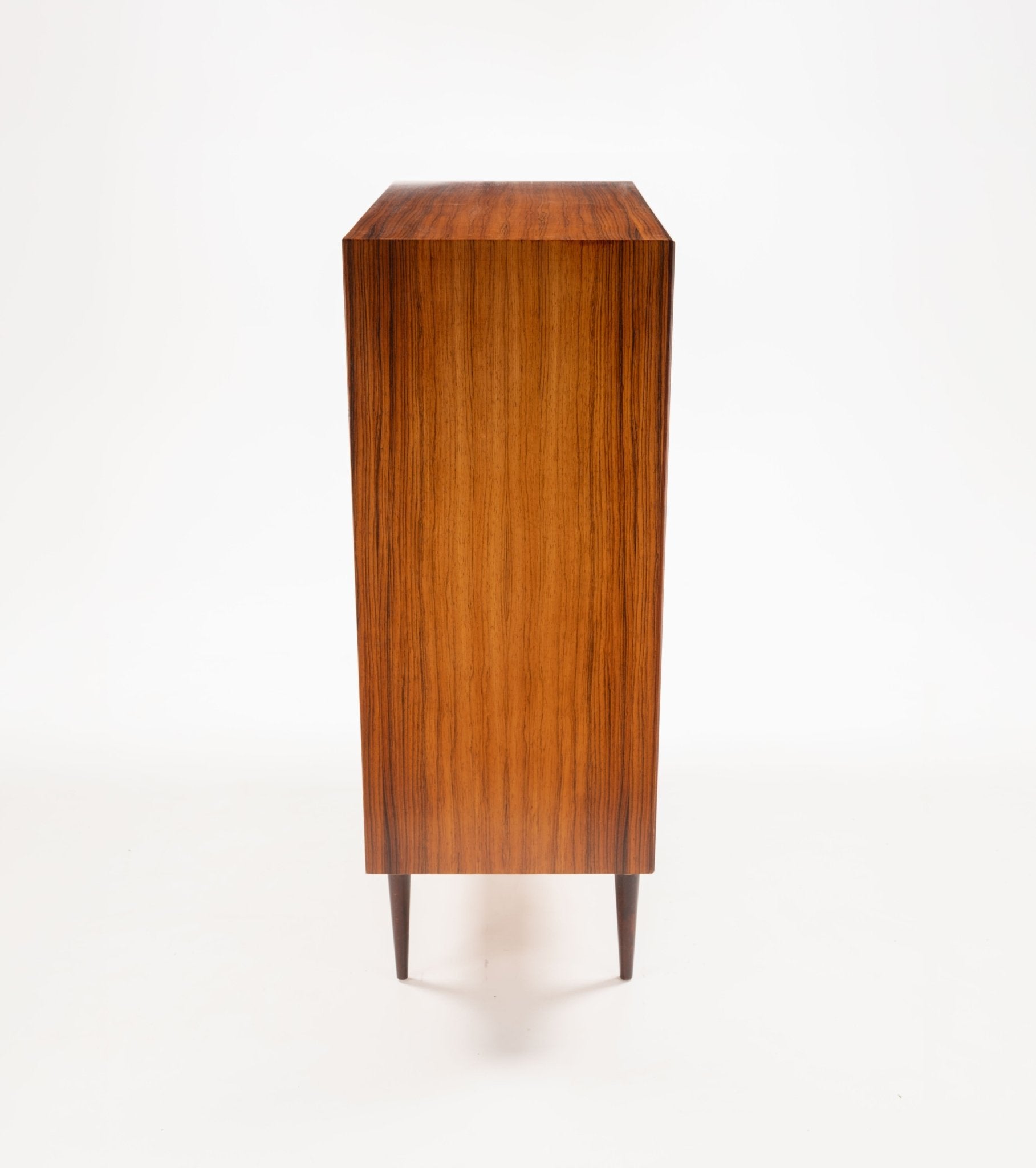 Side view of mid-century modern rosewood dresser with tapered legs and smooth wood grain finish on white background