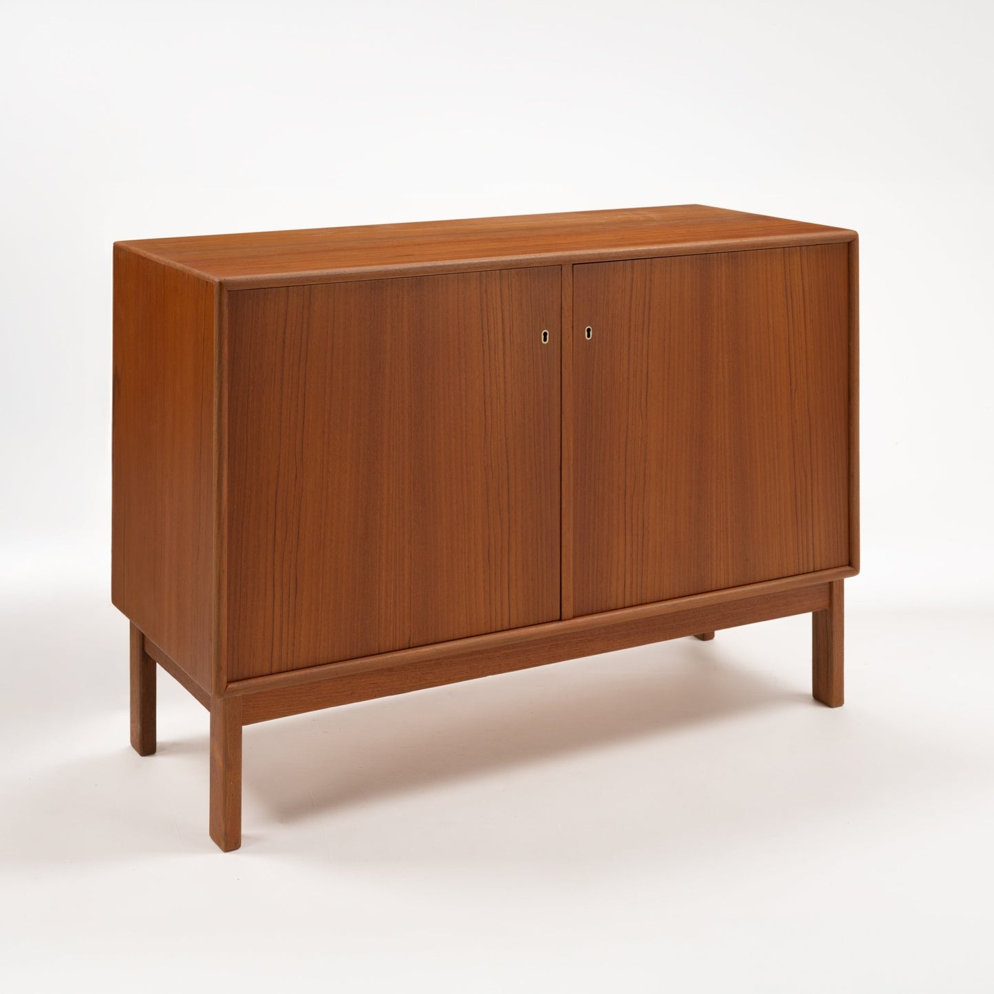 Swedish Teak Cabinet & Bookcase - Set 1 featuring a sleek teak wood storage unit with two closed doors, clean lines, and a raised base showcasing a refined mid century modern furniture style.