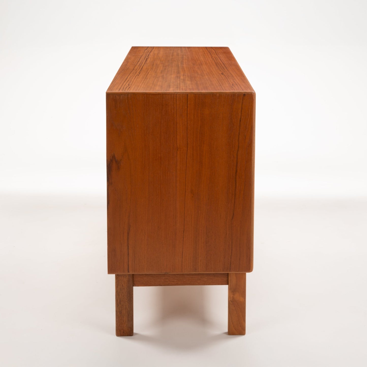 Swedish Teak Cabinet & Bookcase - Set 1 showing a narrow side view of smooth teak wood grain with clean lines and solid wood legs, highlighting minimalist mid century modern furniture design.