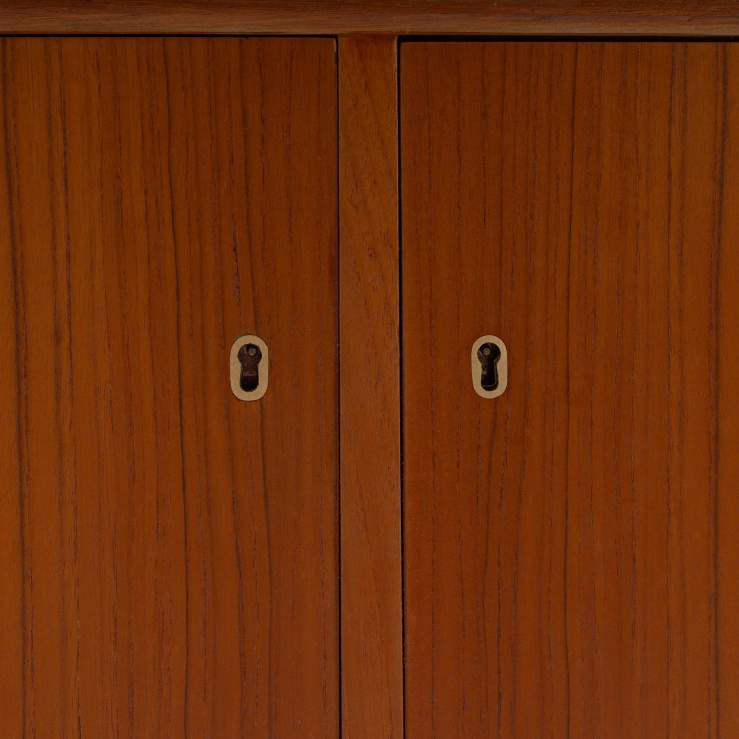 Swedish Teak Cabinet & Bookcase - Set 1 featuring a close-up view of warm teak wood doors with vintage keyhole details and a smooth mid century modern finish.