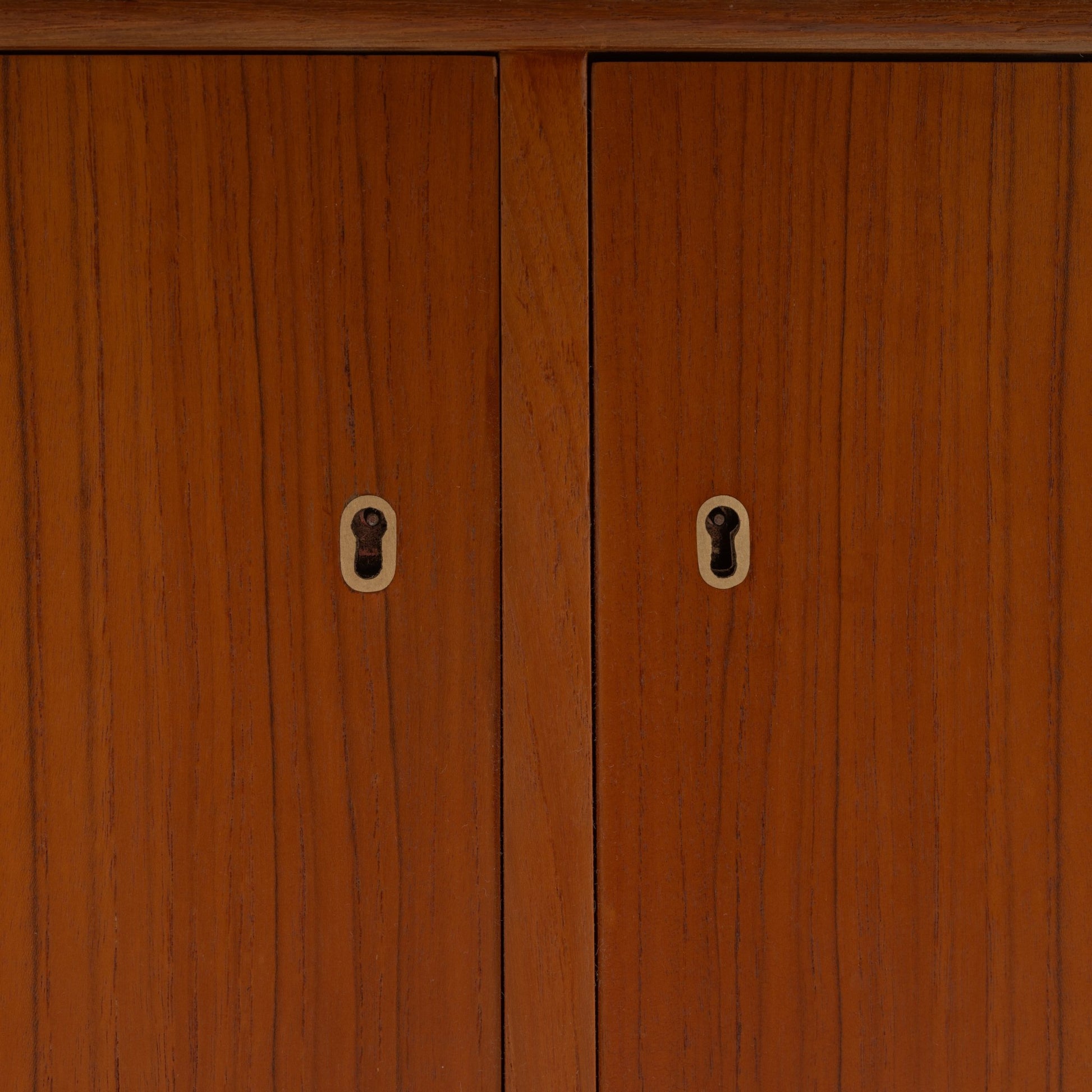 Swedish Teak Cabinet & Bookcase - Set 1 featuring a close-up view of warm teak wood doors with vintage keyhole details and a smooth mid century modern finish.