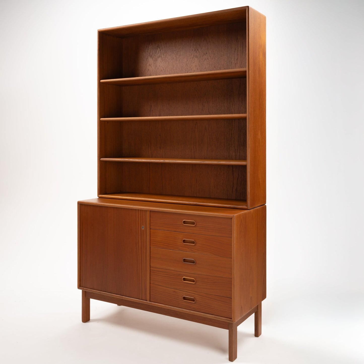 Swedish Teak Cabinet & Bookcase - Set 2 featuring an elegant mid century modern design with spacious open shelves above and a lower section combining five drawers and a single door in warm teak wood.