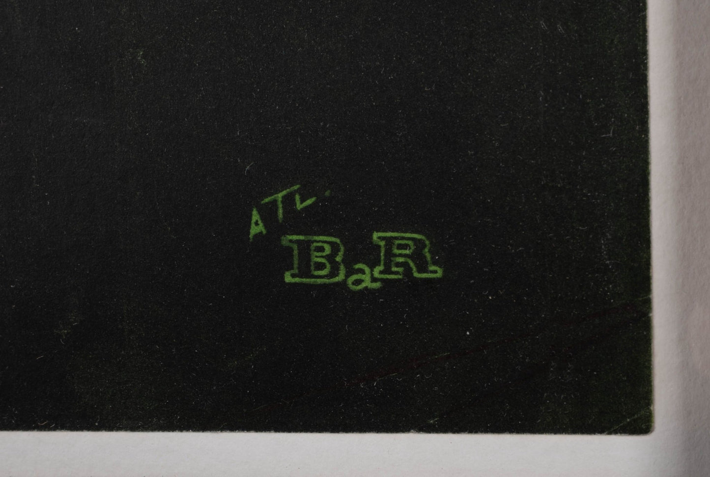 Close-up of green printed signature detail on black linen-backed vintage travel poster corner.