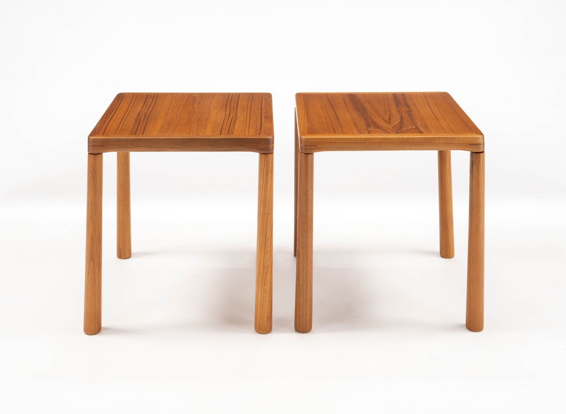Pair of mid-century modern teak side tables with oak legs and finger joint details on top corners on white background