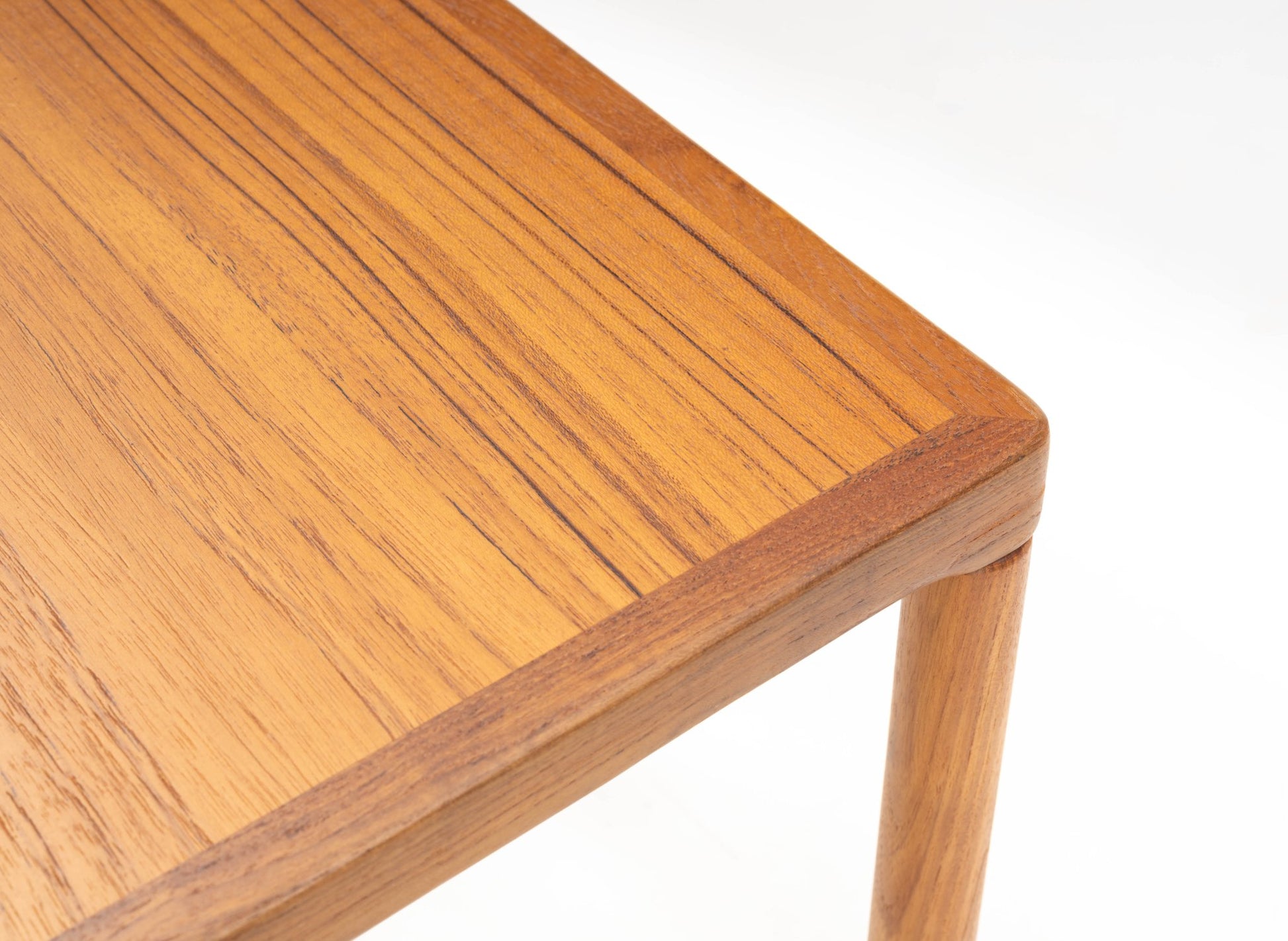 Close-up of mid-century modern teak side table corner with finger joint detail and oak tapered leg on white background