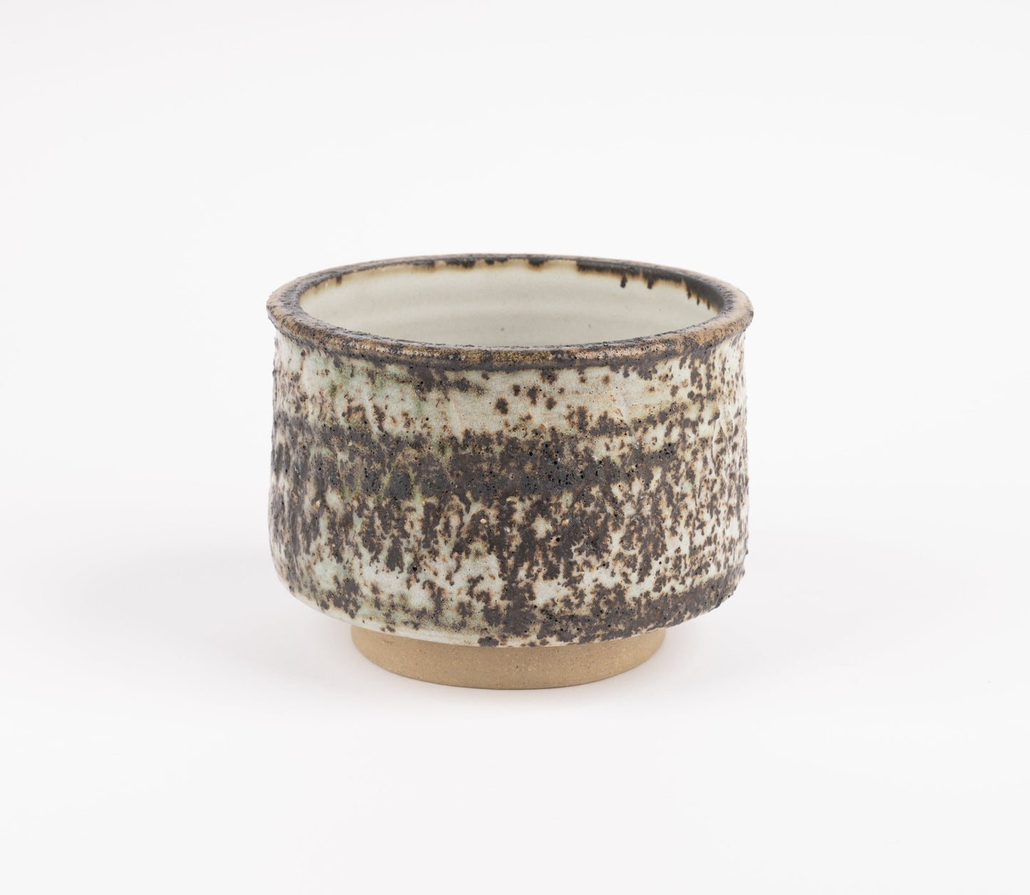Tessa Kidick studio pottery bowl with low cylindrical form and speckled mottled glaze in earthy tones on raised foot
