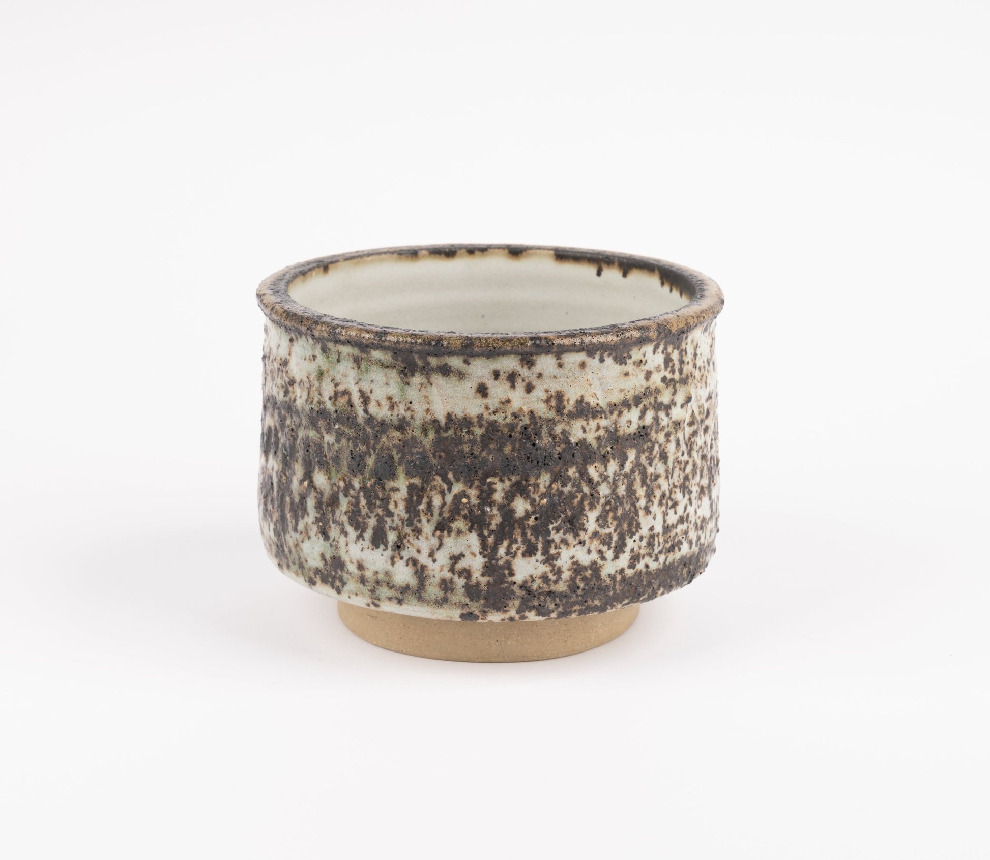 Tessa Kidick studio pottery bowl with low cylindrical form and speckled mottled glaze in earthy tones on raised foot