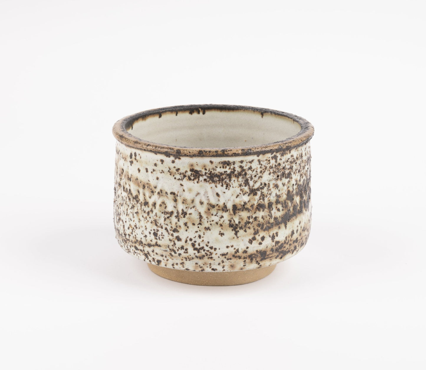 Tessa Kidick studio pottery bowl with low cylindrical form, speckled ivory and brown mottled glaze on raised foot