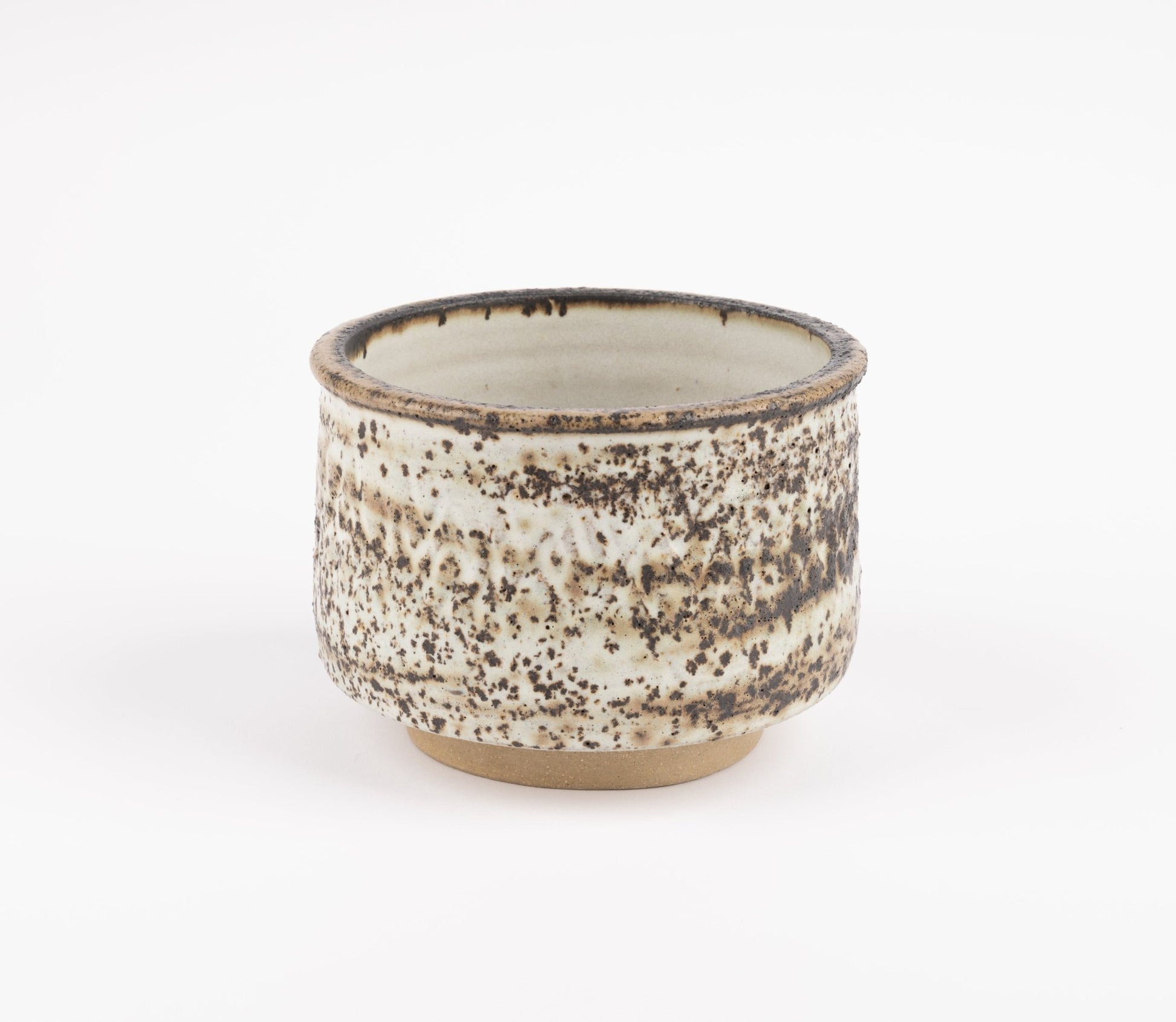 Tessa Kidick studio pottery bowl with low cylindrical form, speckled ivory and brown mottled glaze on raised foot