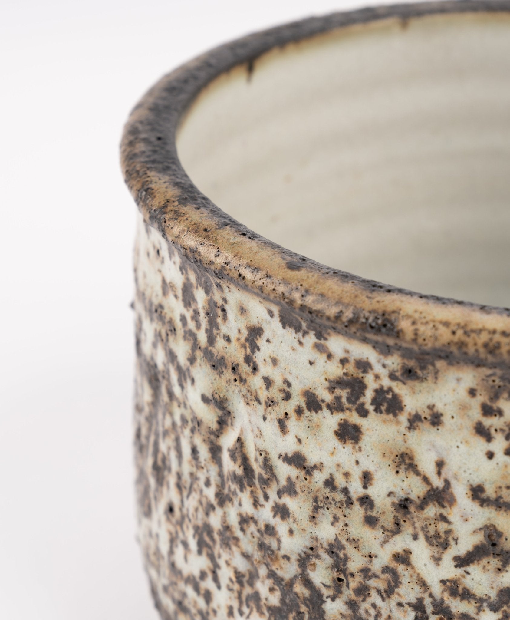 Close-up of Tessa Kidick studio pottery bowl with mottled ivory, charcoal, and brown glaze on raised foot base