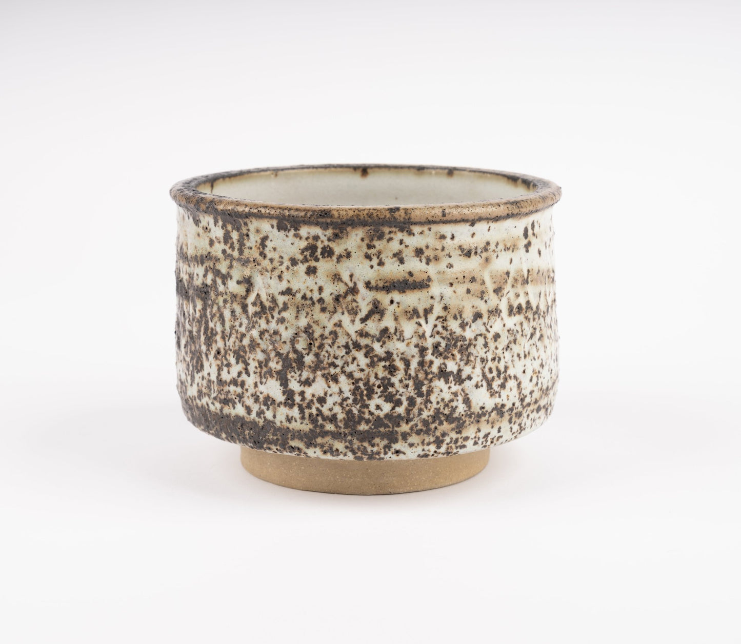 Tessa Kidick studio pottery bowl with low cylindrical form and mottled ivory, charcoal, and brown glaze on raised foot