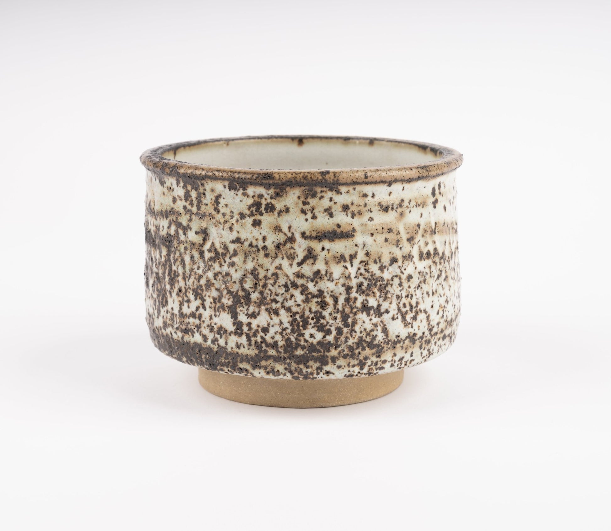 Tessa Kidick studio pottery bowl with low cylindrical form and mottled ivory, charcoal, and brown glaze on raised foot