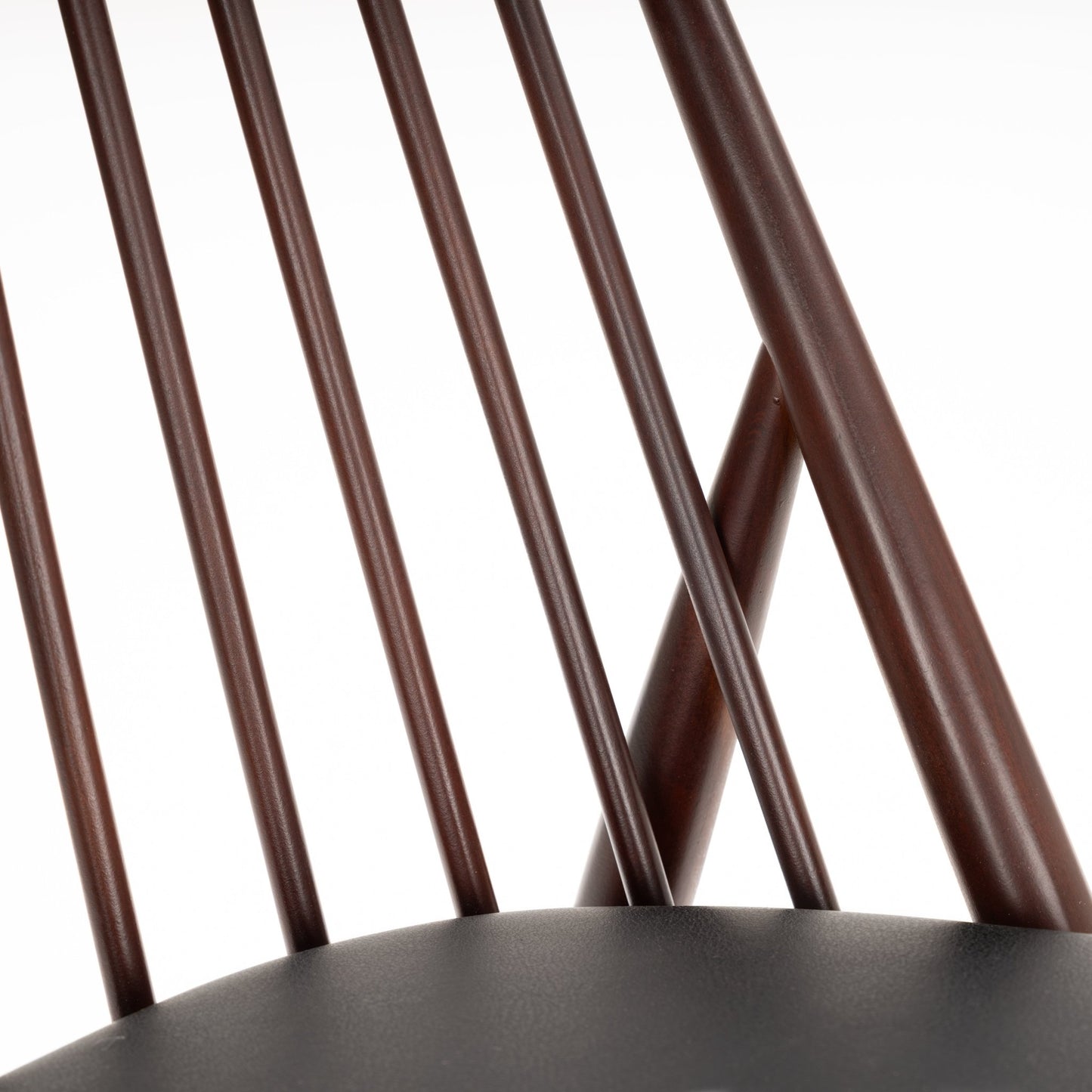 Close-up of dark brown wooden chair backrest with thin rounded vertical spindles and smooth curved upper rail