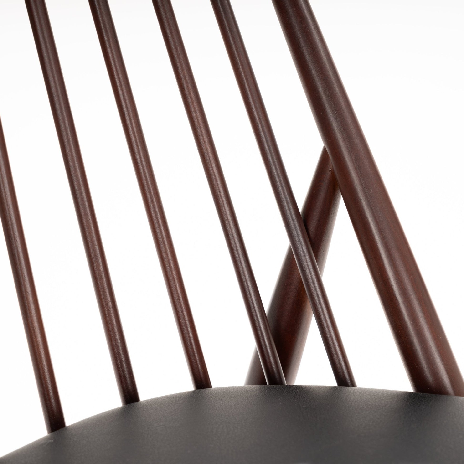 Close-up of dark brown wooden chair backrest with thin rounded vertical spindles and smooth curved upper rail
